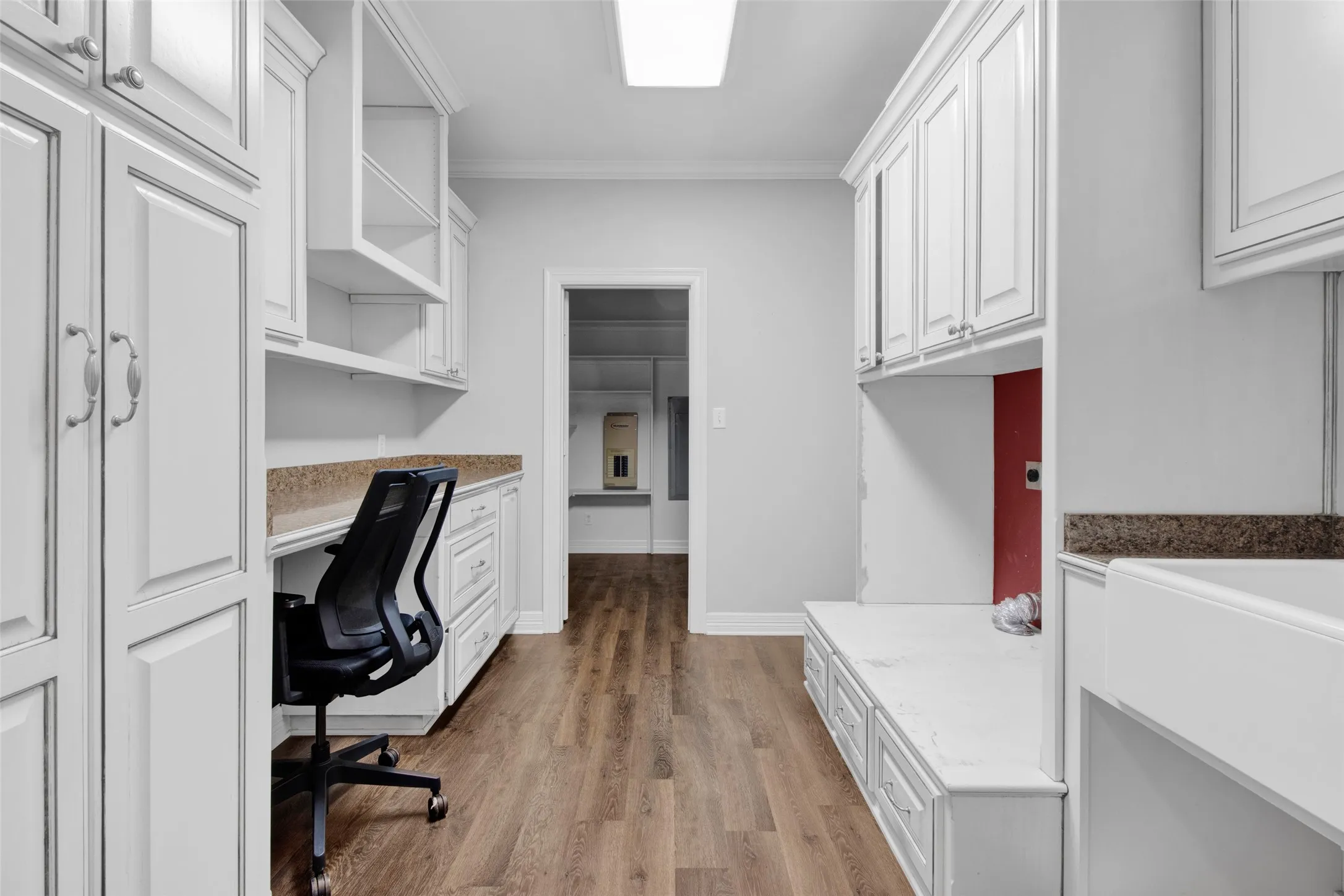 Dedicated office nook with built-in desk, wood-finish flooring, white shaker cabinetry, and stone-finish countertops