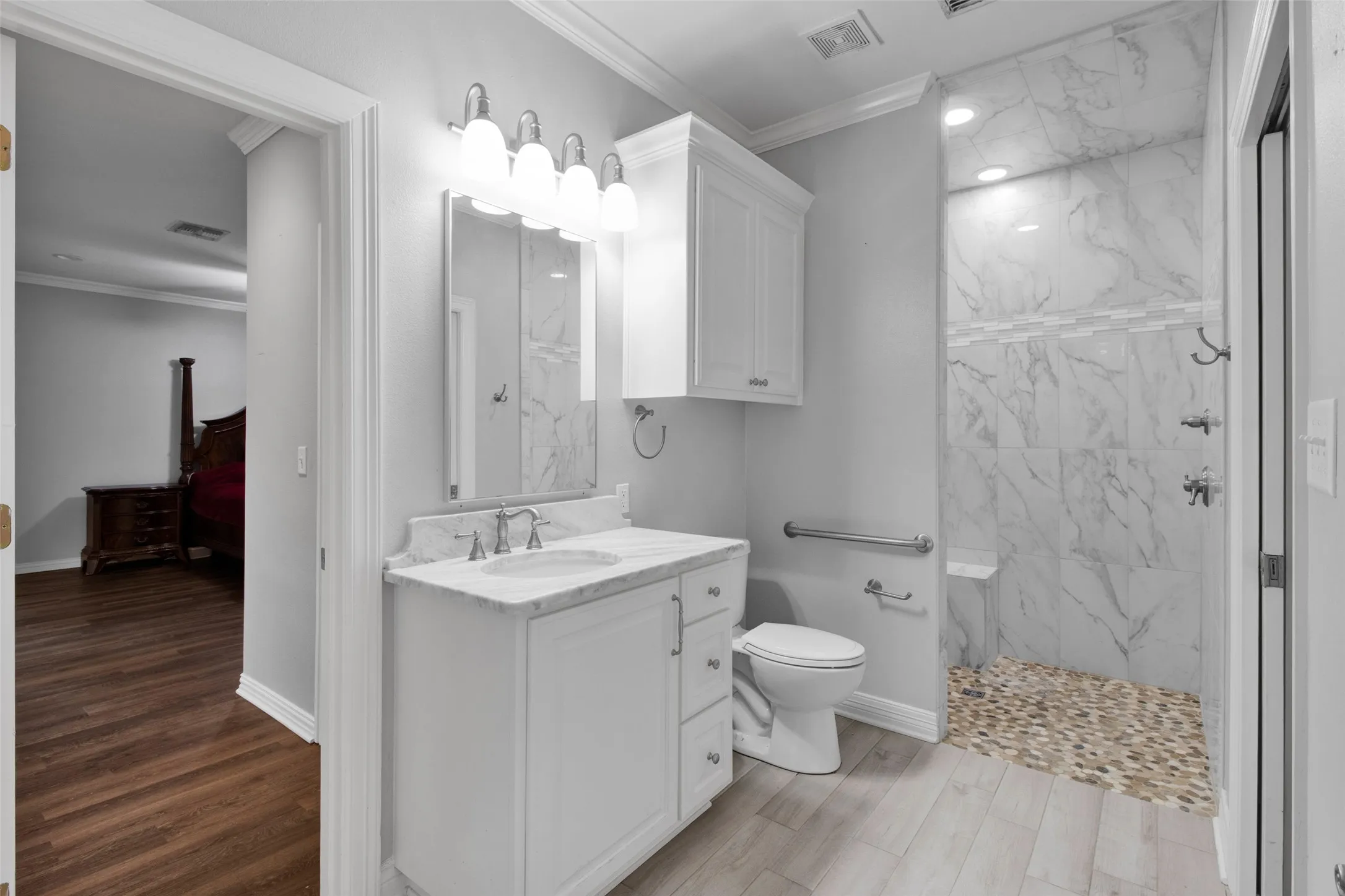 Bathroom featuring a white vanity with a rectangular sink, a walk-in shower with stone tile flooring, marble-look wall tiling, and a built-in shower bench