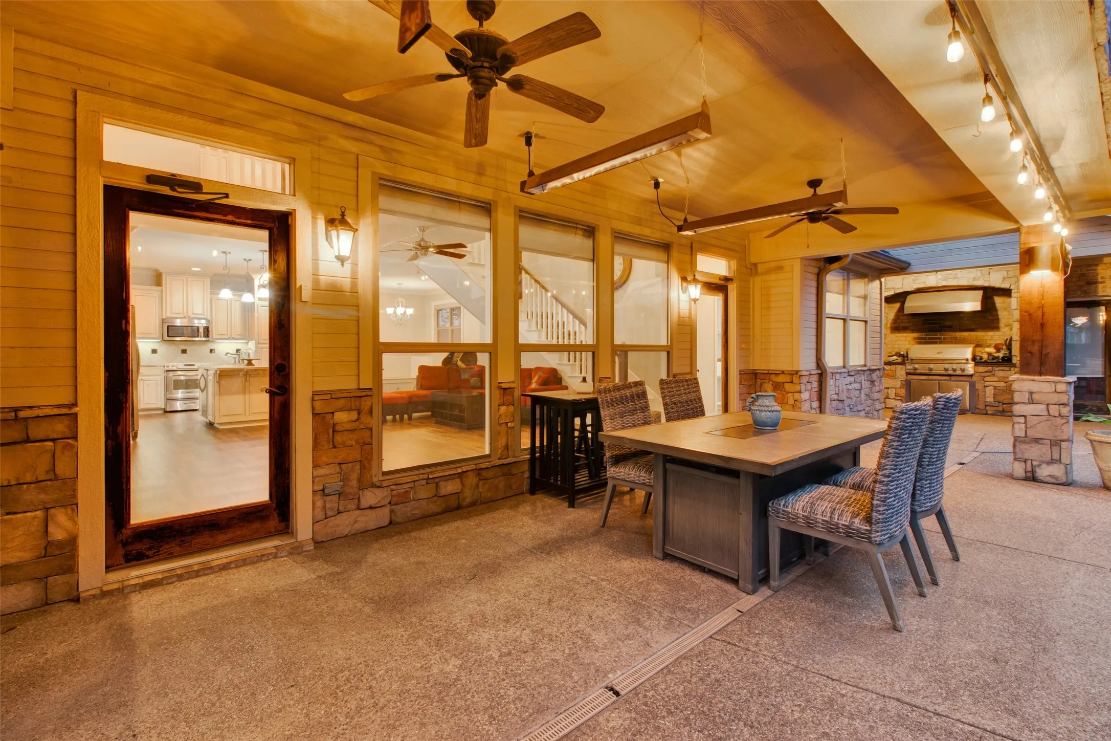 Expansive outdoor patio featuring a built-in grill station, outdoor ceiling fans, recessed lighting, and stone accents
