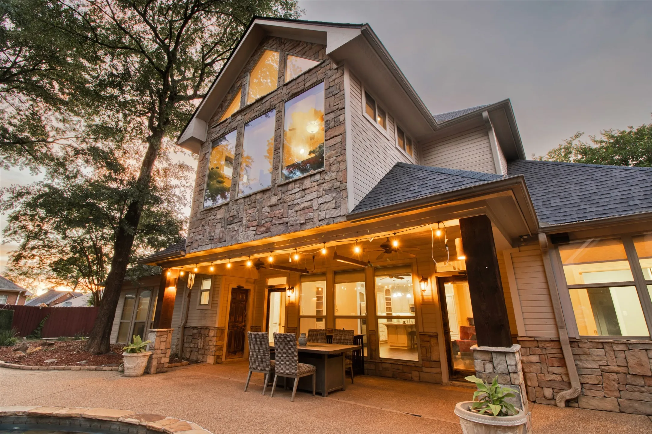 Exterior featuring a stone and siding facade, multi-pane windows, and a covered patio