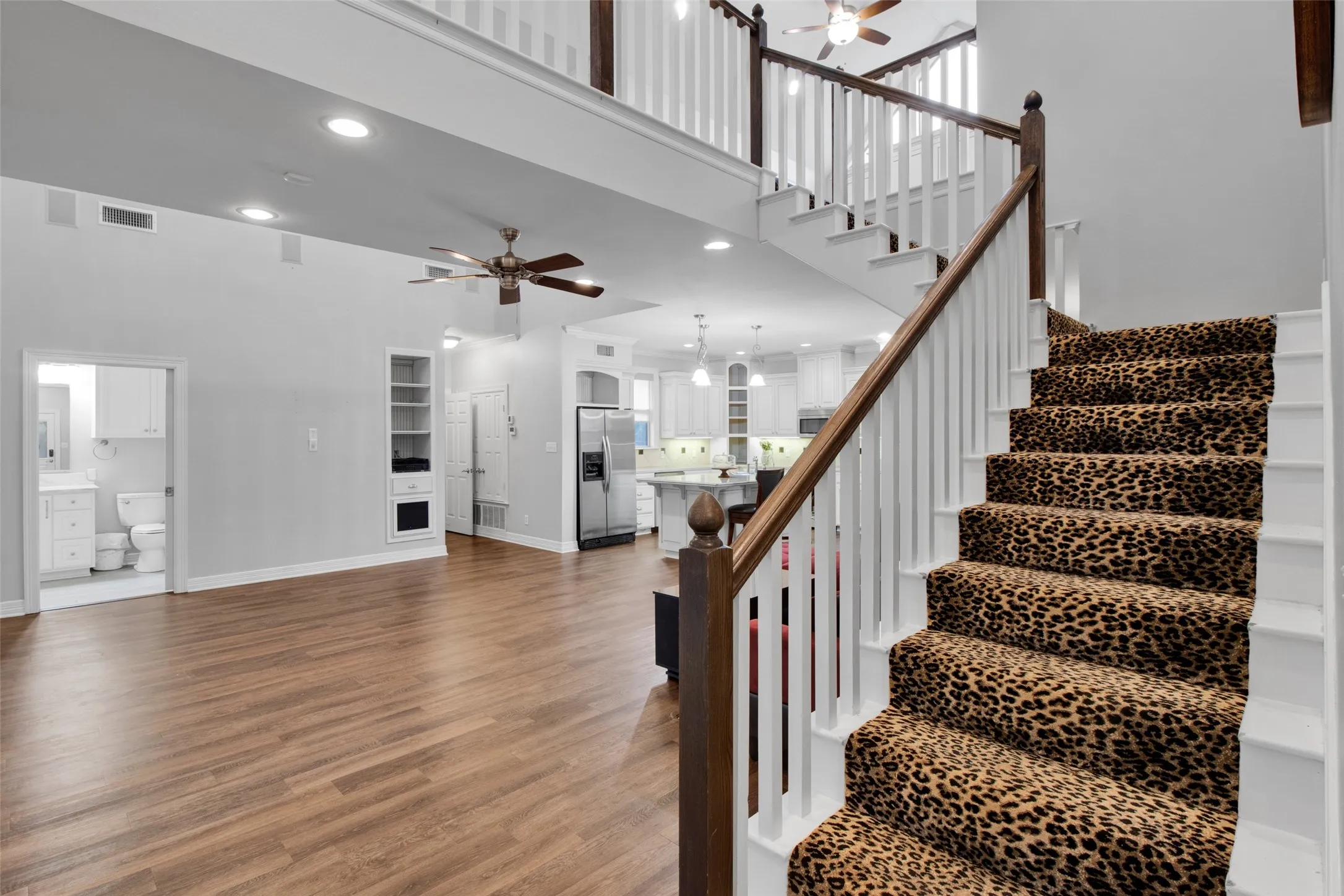 Two-story interior featuring wood-finish flooring and a staircase with a leopard print runner