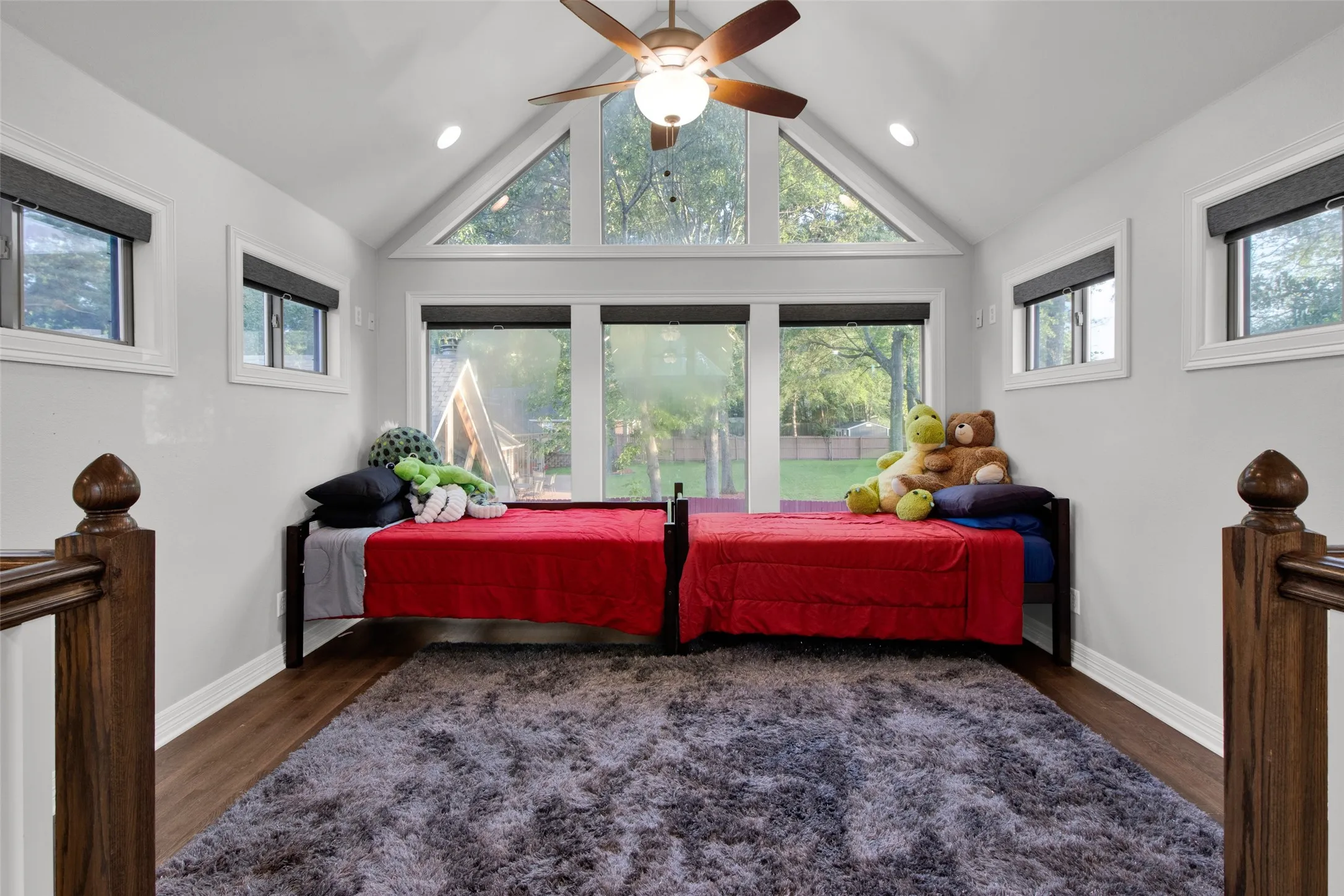 Upper-level room featuring wood-finish flooring, a vaulted ceiling with a ceiling fan, recessed lighting, and a large window array including a triangular transom
