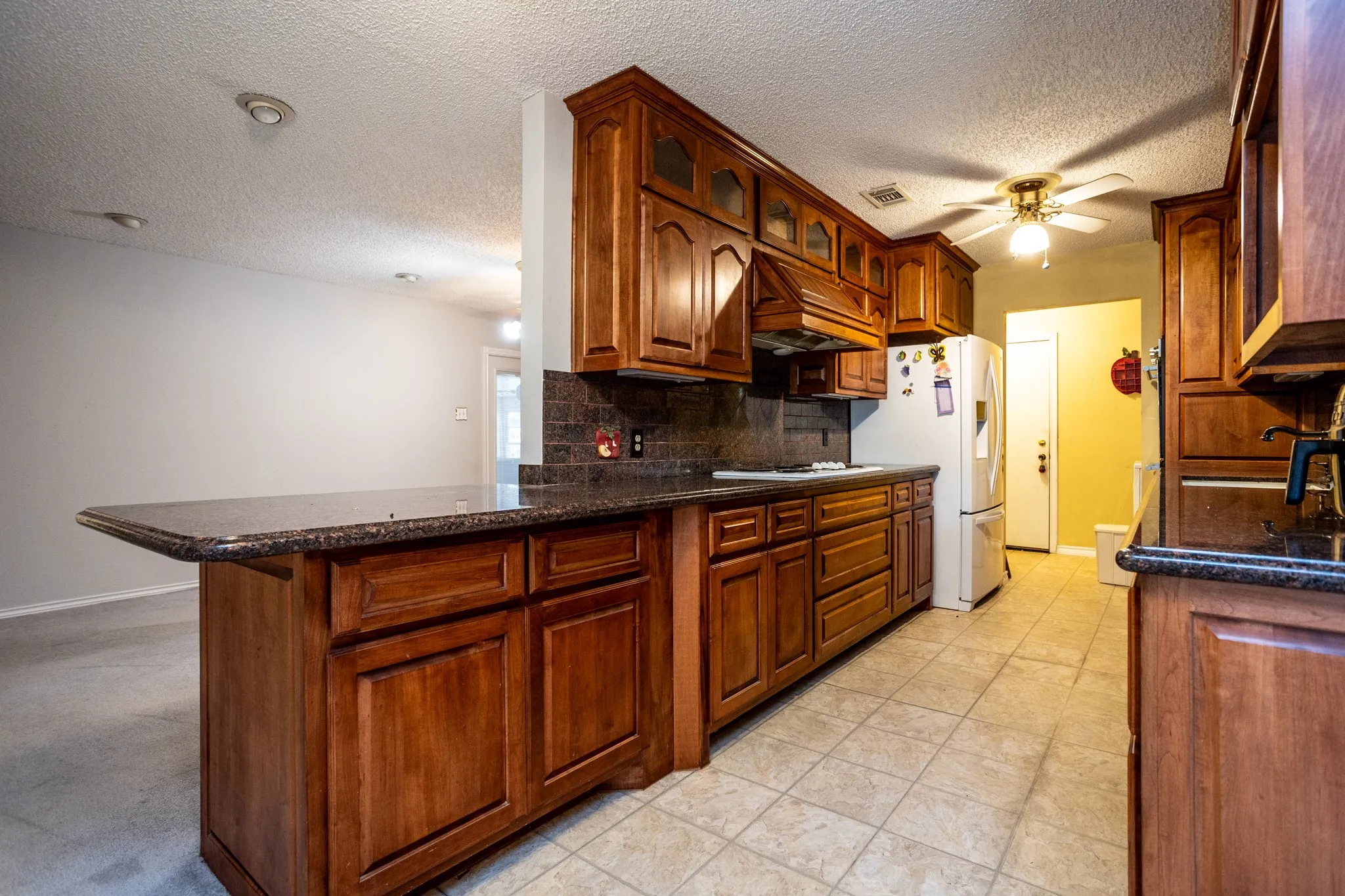 Galley kitchen has beautiful wood cabinets with uppers having lighted glass for displays