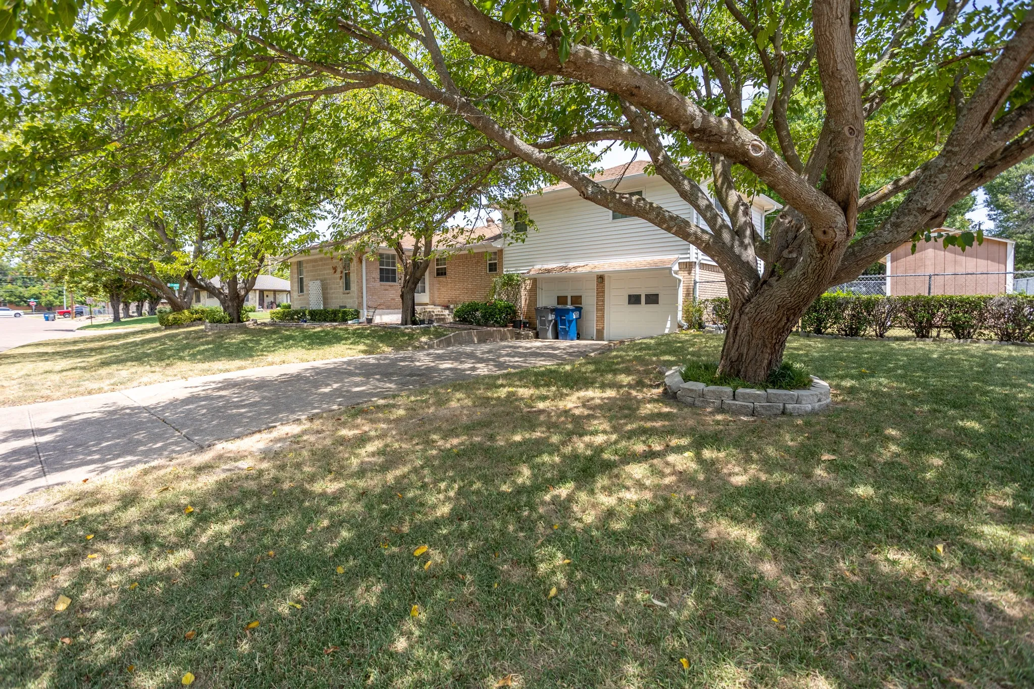 Side view shows door from dining area, garage entrance with 2 bedrooms above the garage.  Garage is lower then main floor with steps that includes chair lift from garage to kitchen area. Trees shade west side.