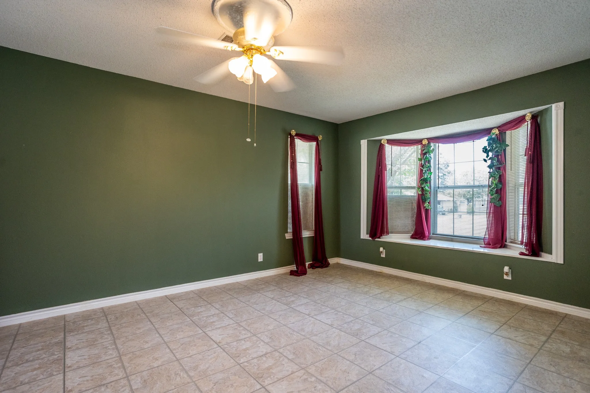 Spacious dining space has box window and ceiling fan.