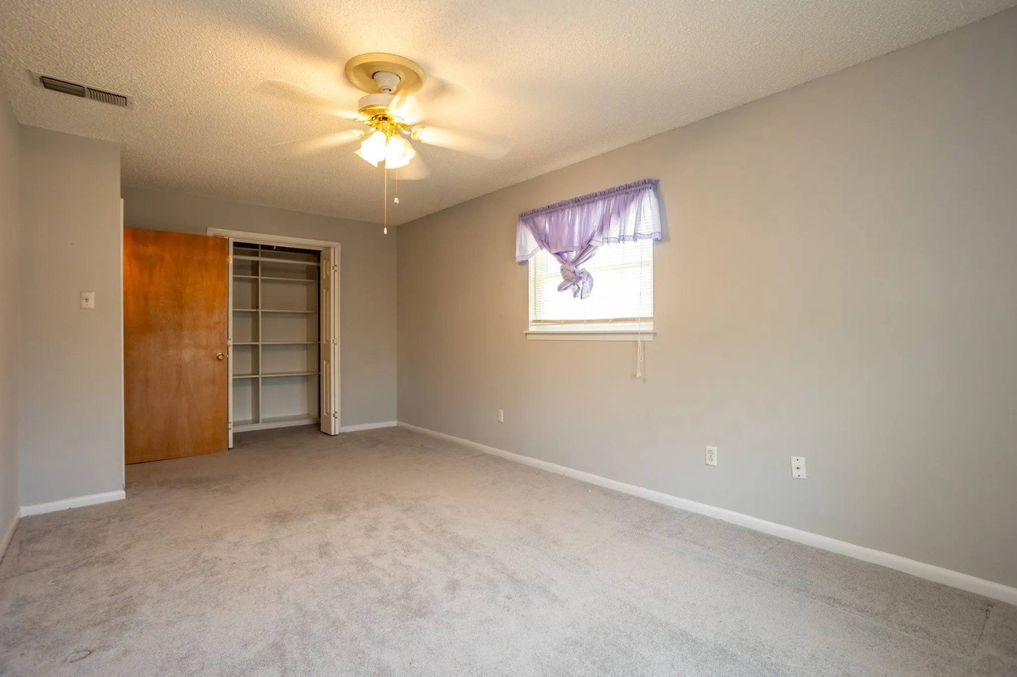 Upstairs bedroom features ceiling fan and good closet.