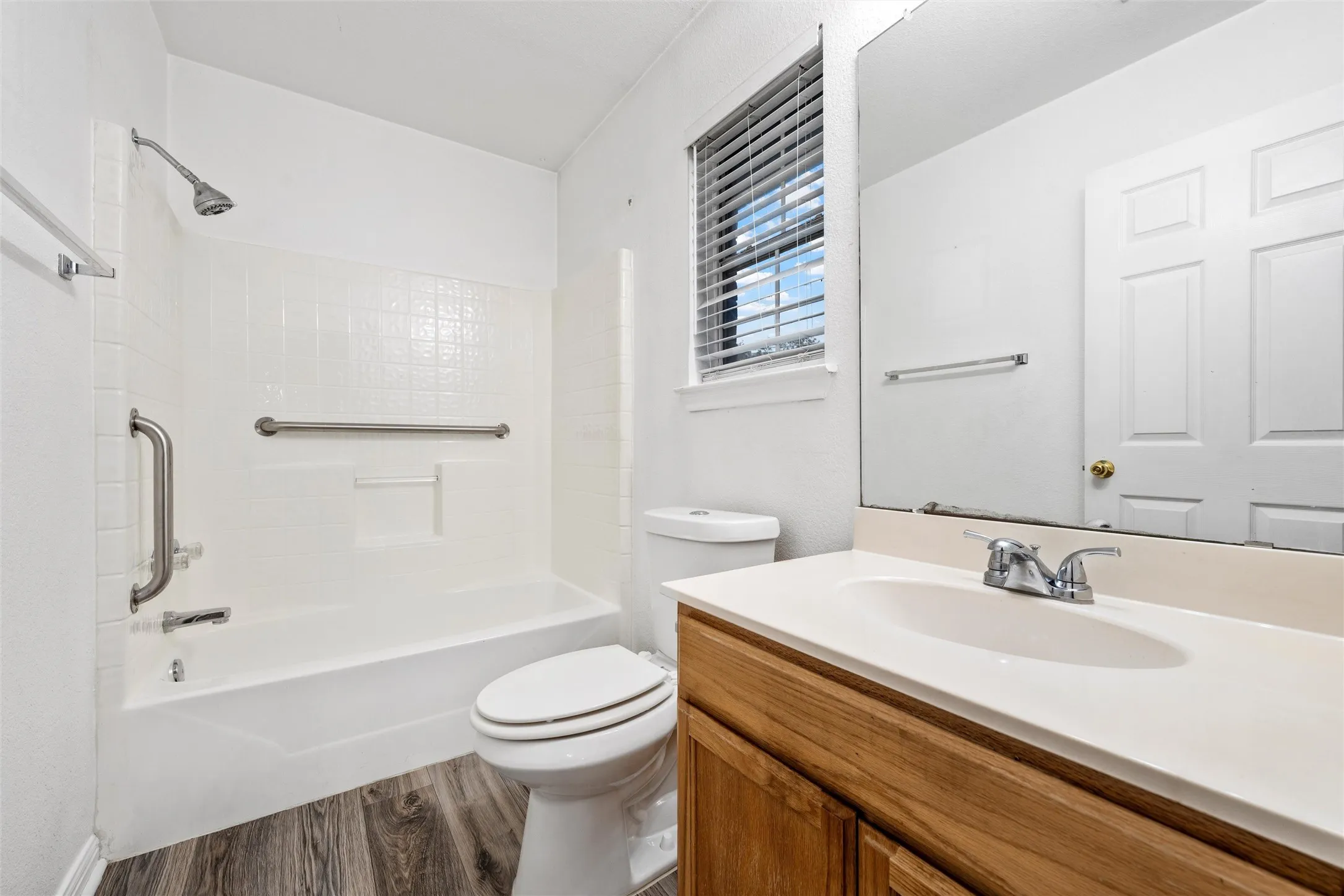 Bathroom with wood finished floors, bathtub / shower combination, vanity, and toilet