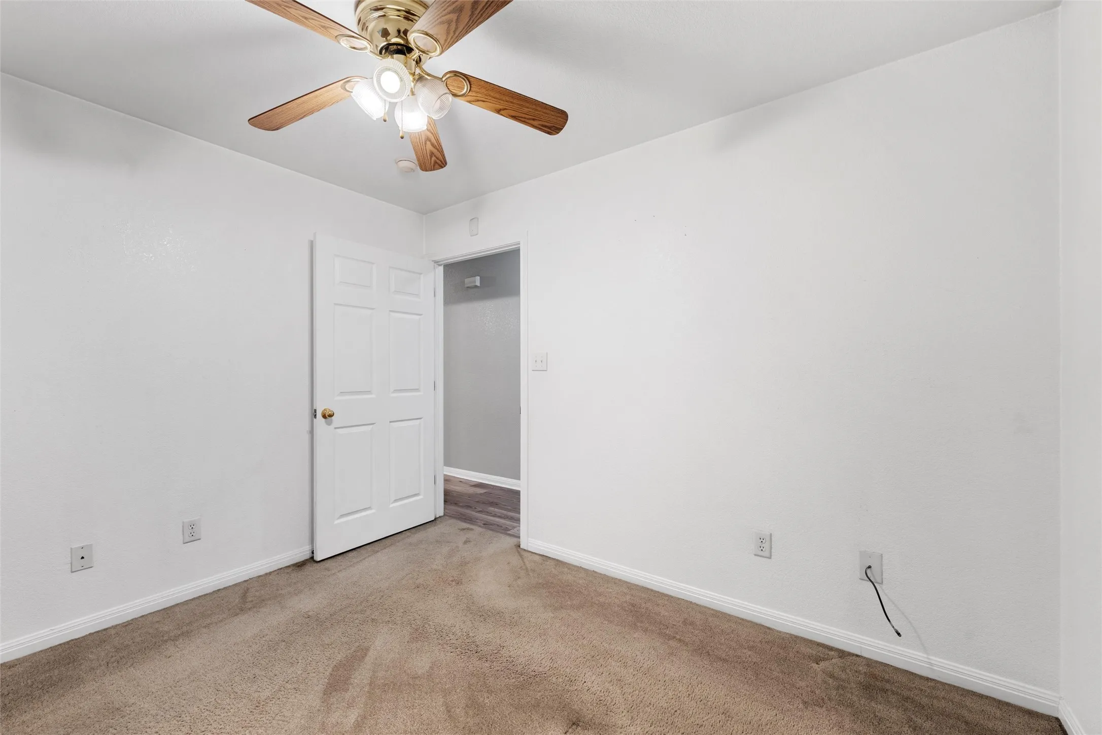 Carpeted spare room featuring baseboards and a ceiling fan