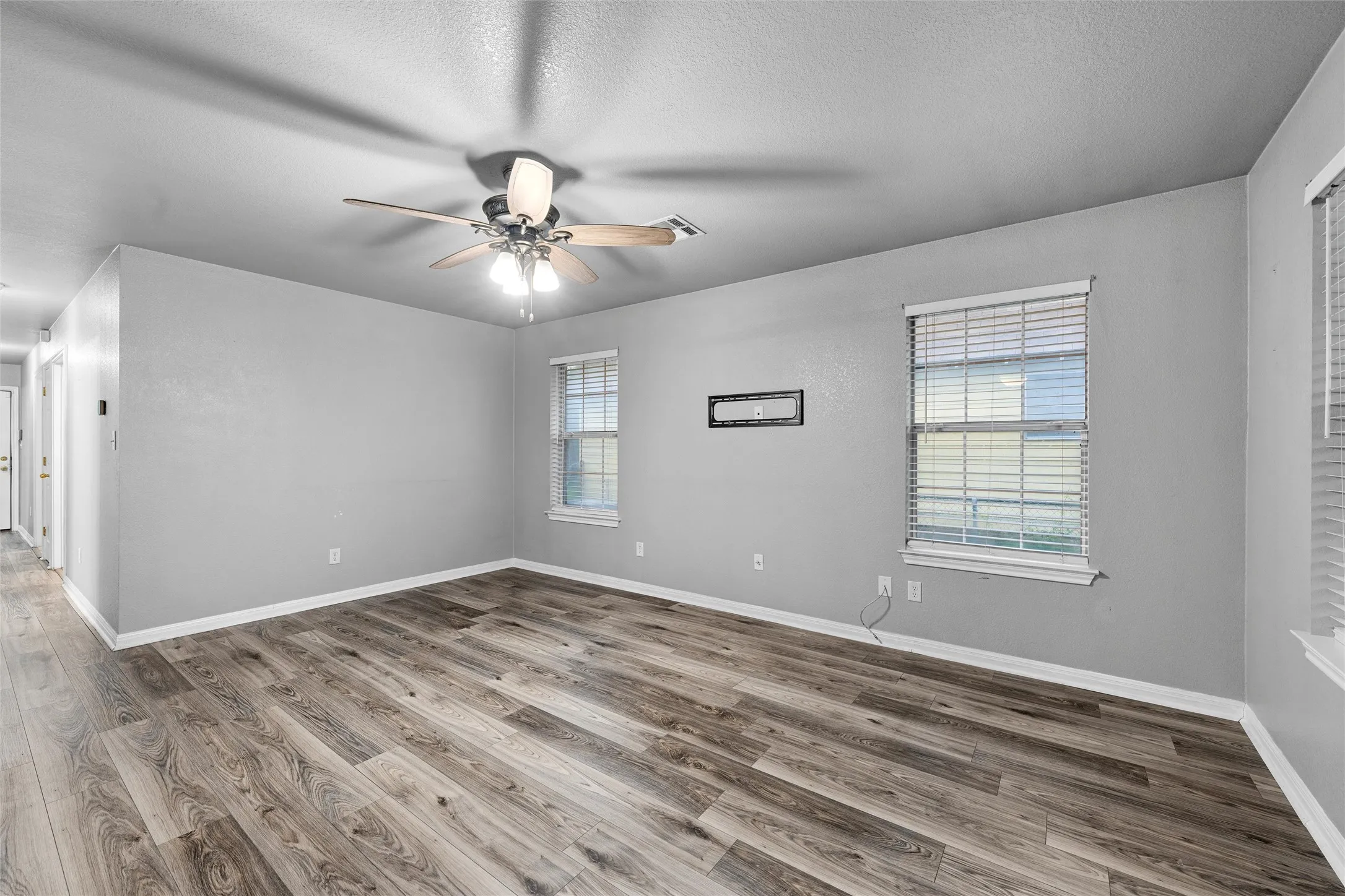Unfurnished room featuring ceiling fan, wood finished floors, baseboards, and a textured ceiling
