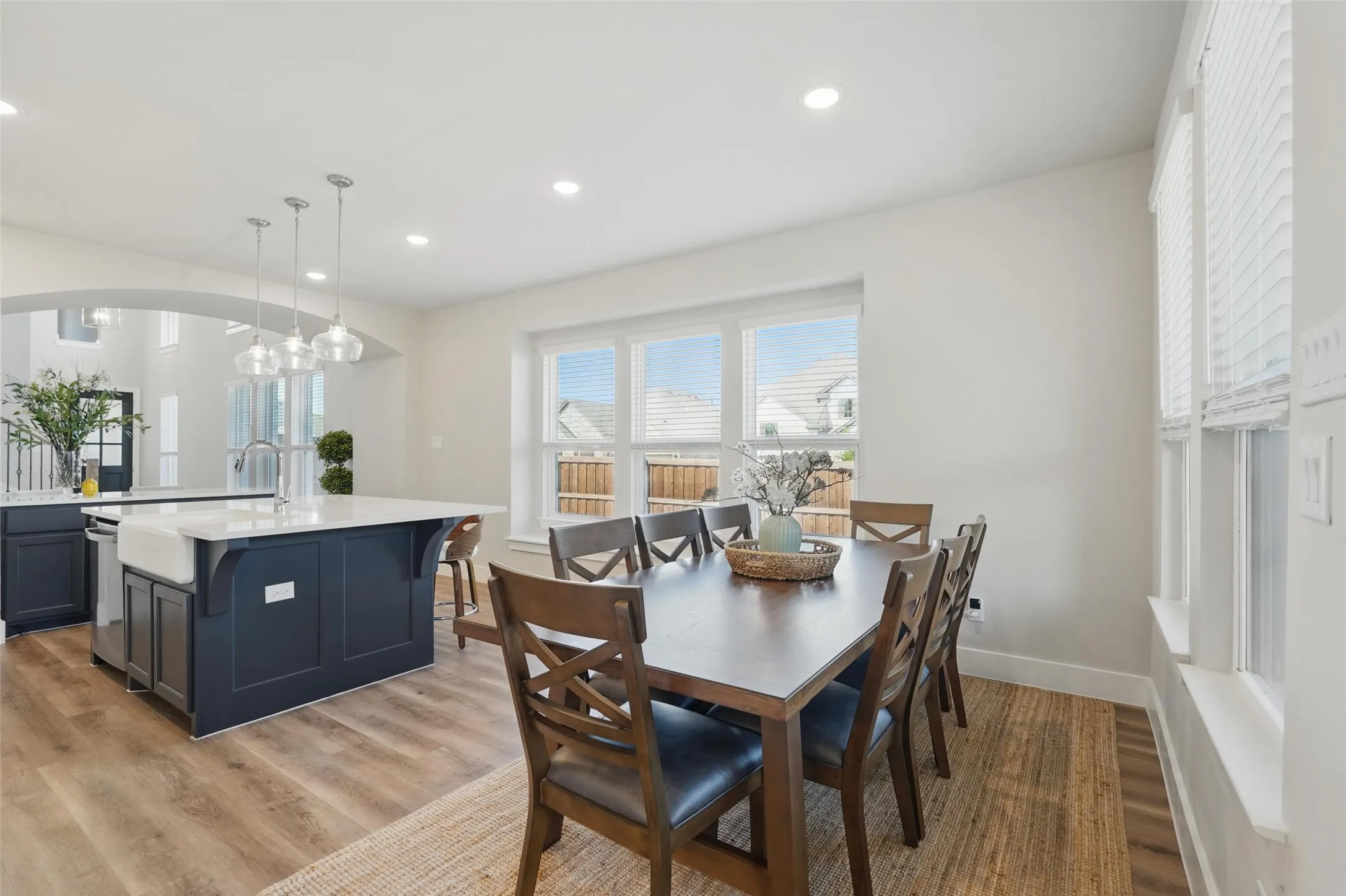 Open-concept layout featuring wood-finish flooring, recessed lighting, and an island with a farmhouse sink