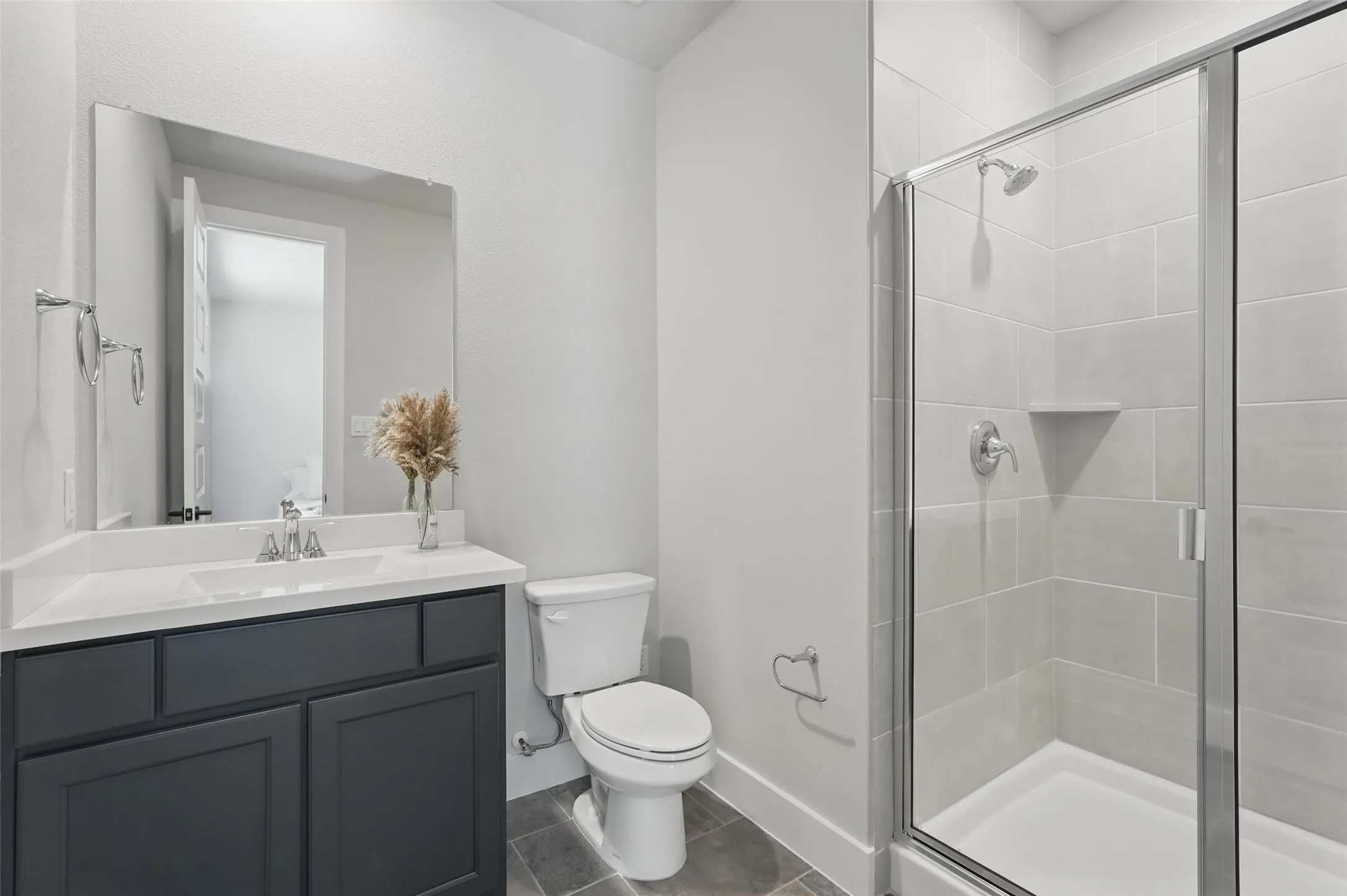 Modern bathroom featuring a dark navy vanity with ample storage, white quartz countertop, chrome faucet fixtures, and a large framed mirror