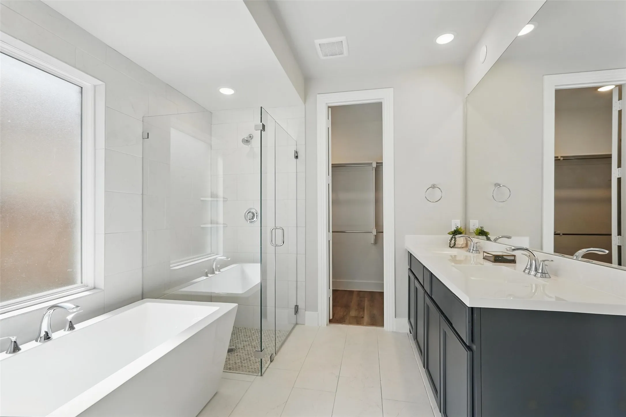 Freestanding soaking tub, glass-enclosed shower, dual vanity with undermount sinks, and a large wall-mounted mirror