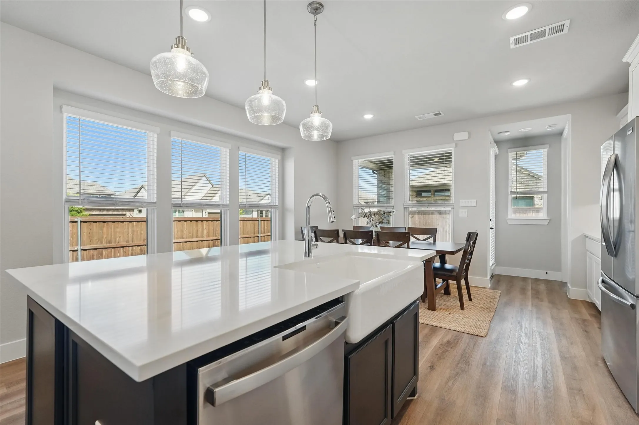 Modern kitchen featuring a large waterfall-edge island with white quartz countertops, stainless steel appliances, and an undermount sink