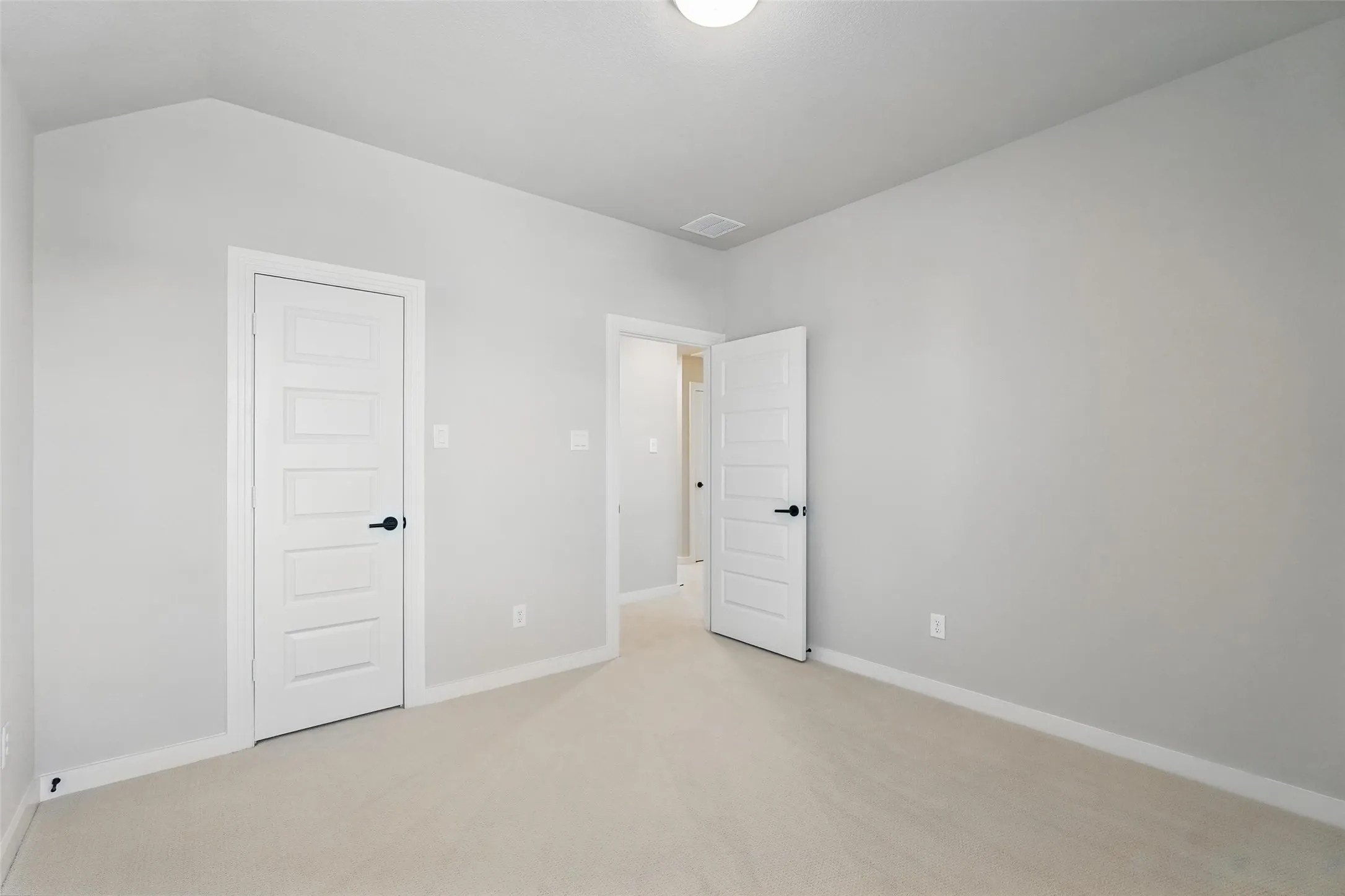 Bright, light-filled bedroom featuring pristine white panel doors, neutral carpet flooring, and recessed ceiling lighting