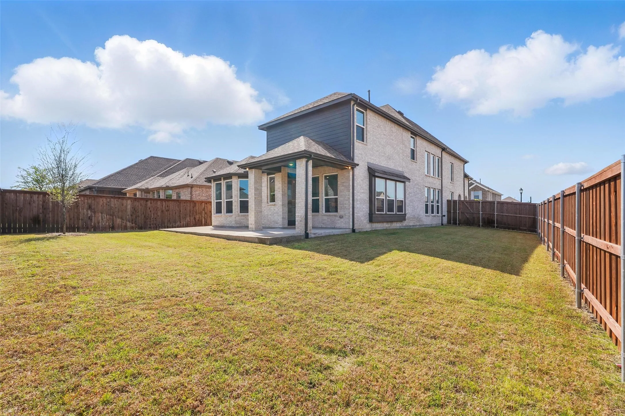 Modern farmhouse exterior with clean-lined architecture, featuring a two-story design with board-and-batten siding, large multi-pane windows, and a covered front porch