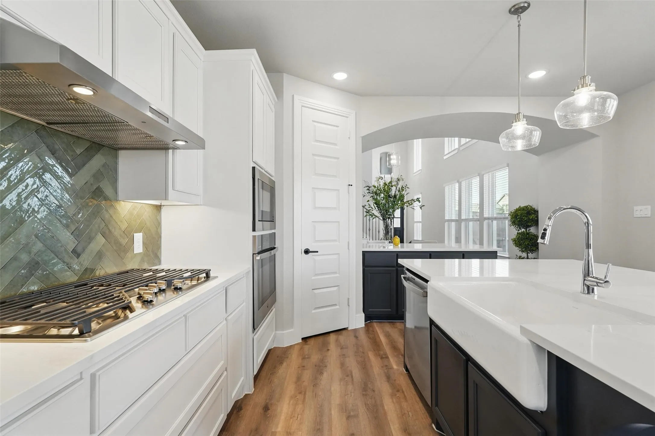 Gourmet kitchen featuring a gas range, herringbone tile backsplash, stainless steel appliances, double ovens, and a farmhouse sink