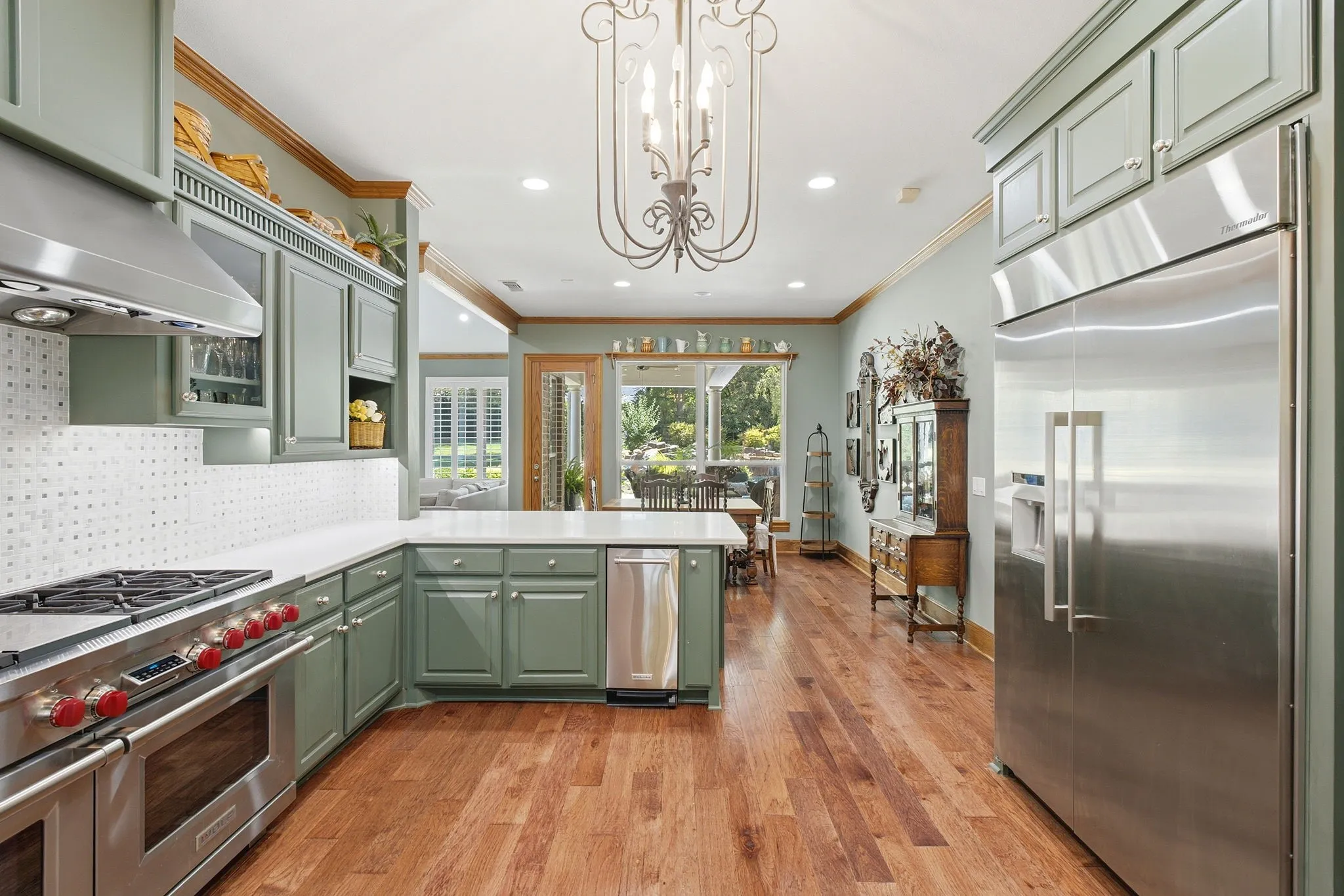 Gourmet kitchen featuring a stainless steel range and hood, integrated refrigerator, light-colored cabinetry, stone countertops, and wood-finish flooring