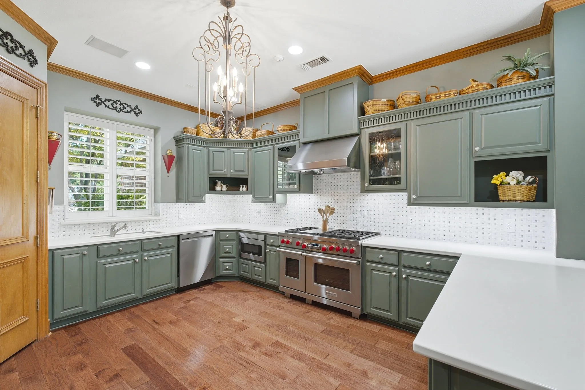 Wood-finish flooring, custom cabinetry with display shelves, stainless steel range with hood, white countertops, and full-height tiled backsplash