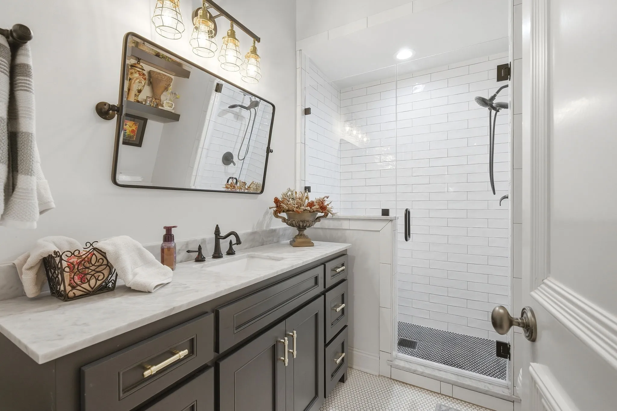 Spa-inspired primary bathroom featuring a charcoal gray vanity with white quartz countertop, oil-rubbed bronze hardware, and integrated sink
