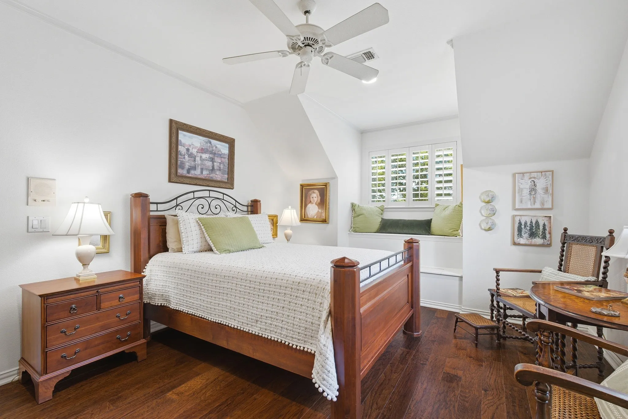 Bright, light-filled bedroom featuring hardwood flooring, a ceiling fan, and plantation shutters
