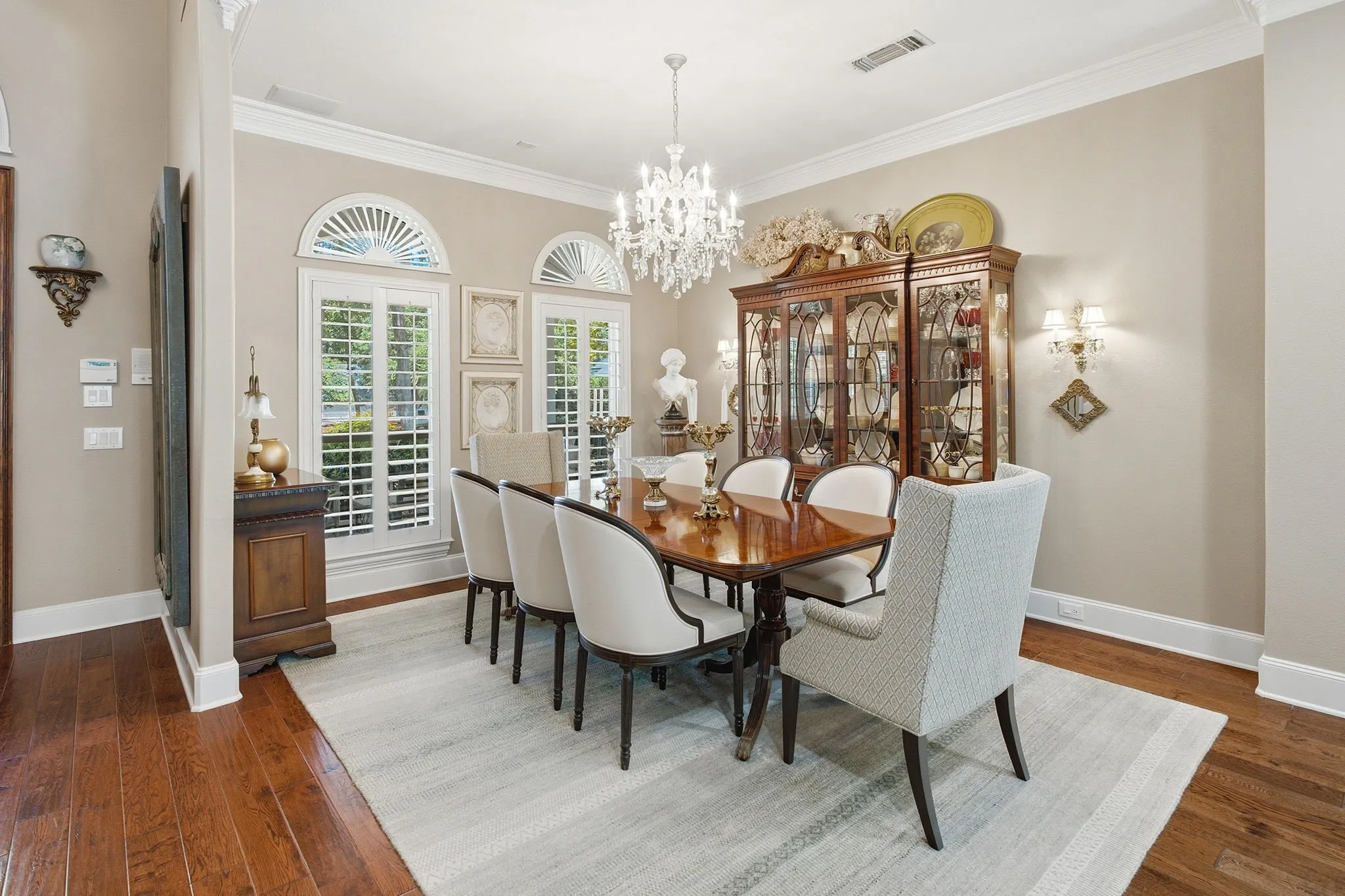 Hardwood flooring, arched transom windows, plantation shutters, crown molding, and wall sconces