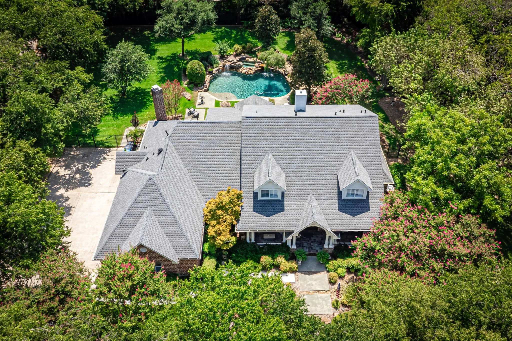 Elegant two-story residence featuring a slate-gray composite roof with distinctive peaked gables and blue-shuttered windows