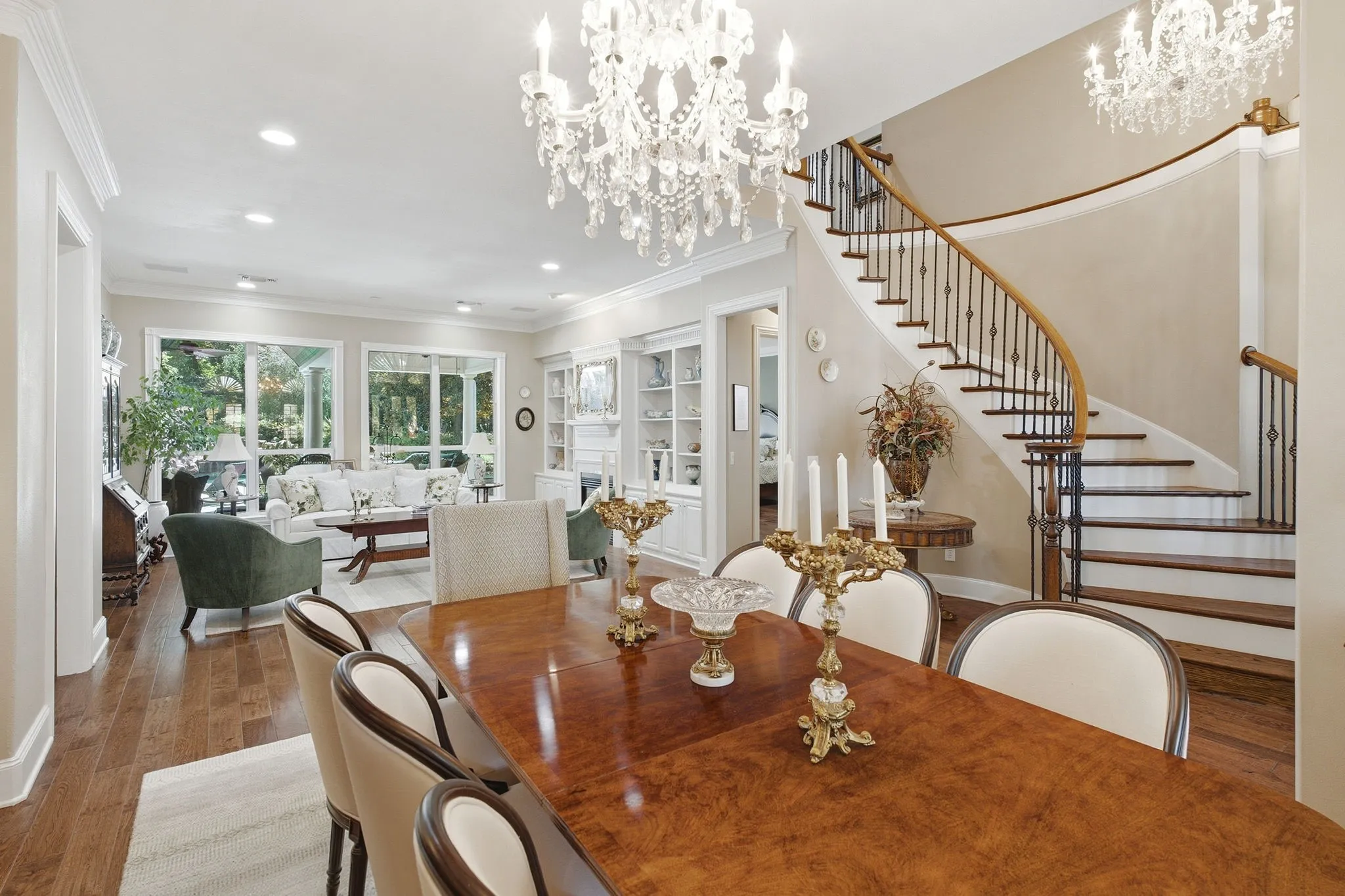 Elegant formal dining room showcasing a rich wood-finish table, crystal chandeliers, and recessed ceiling lighting