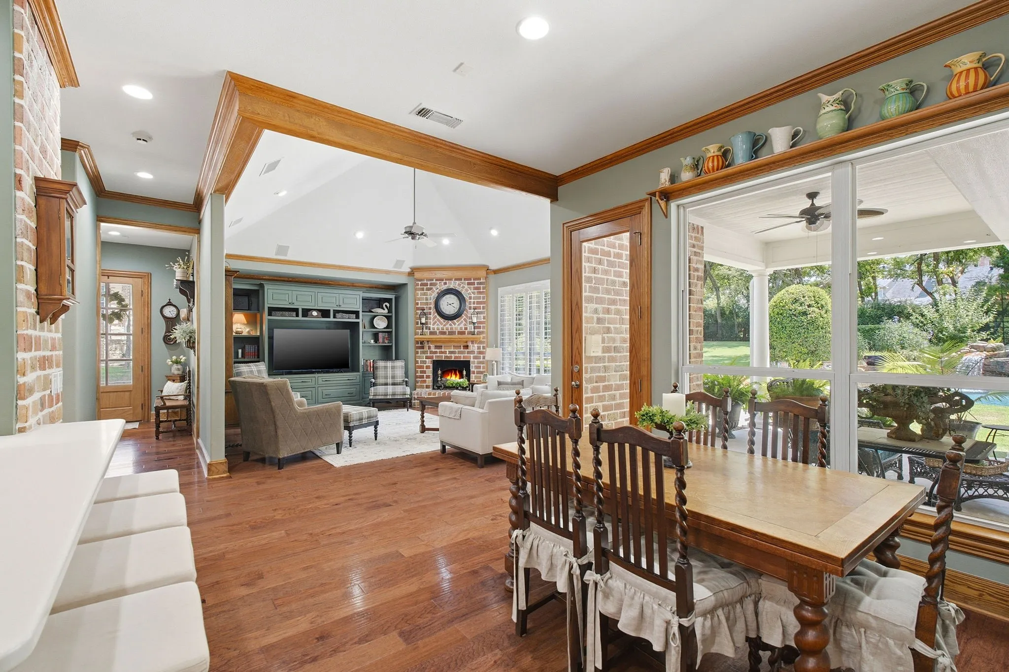 Open-concept living space featuring hardwood flooring, coffered ceiling with wood trim, and large glass sliding doors opening to a screened porch