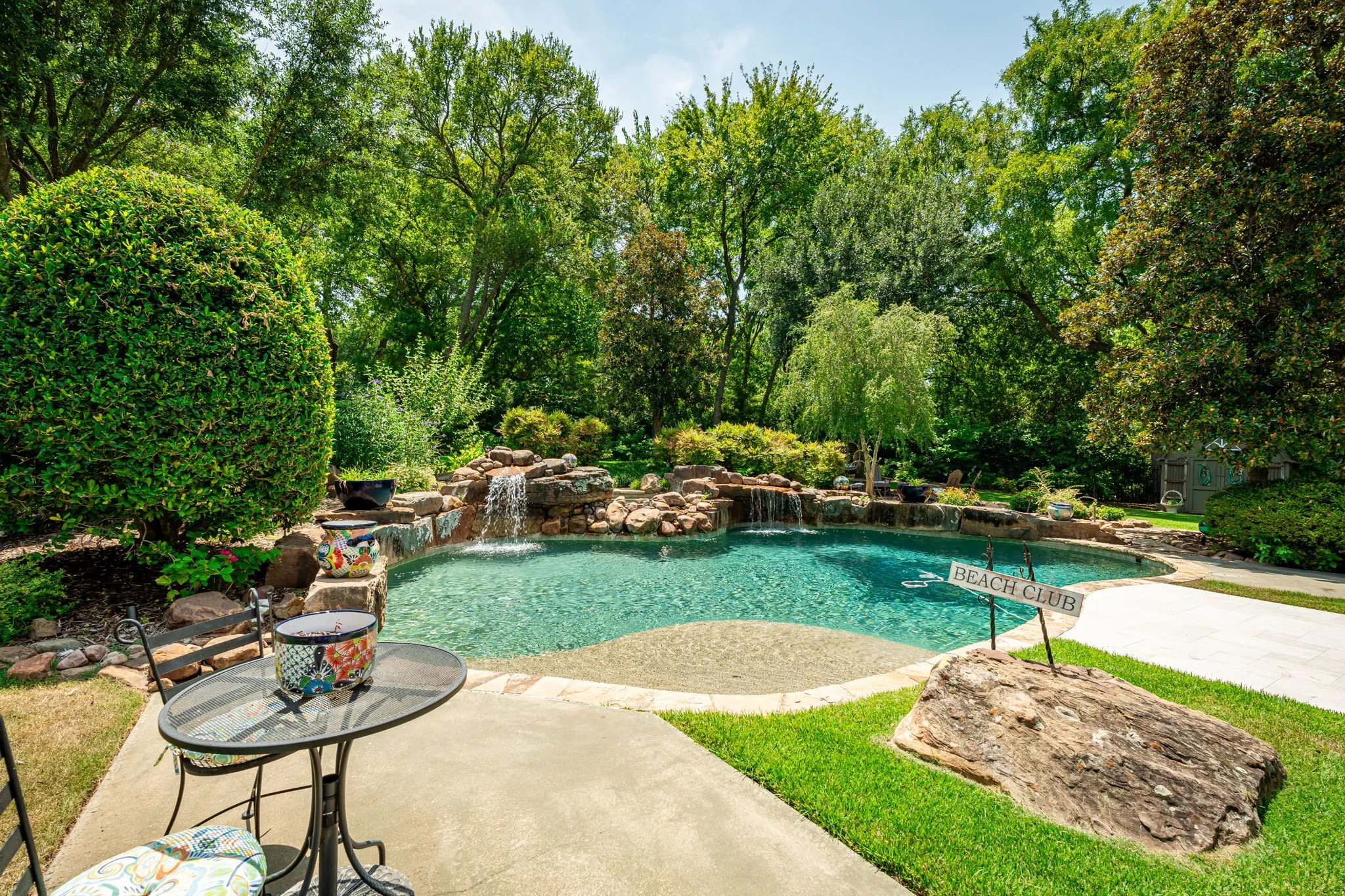 Luxury resort-style backyard oasis featuring a lagoon-form saltwater pool with integrated spa, natural stone waterfall feature, and sun shelf entry