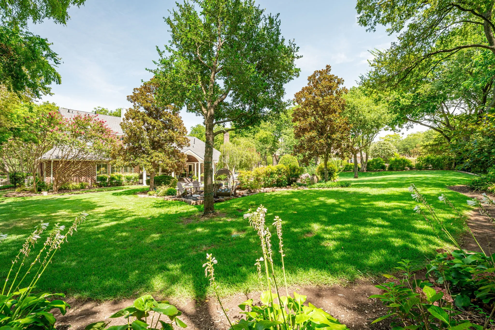 Expansive green lawn surrounded by mature trees and lush landscaping