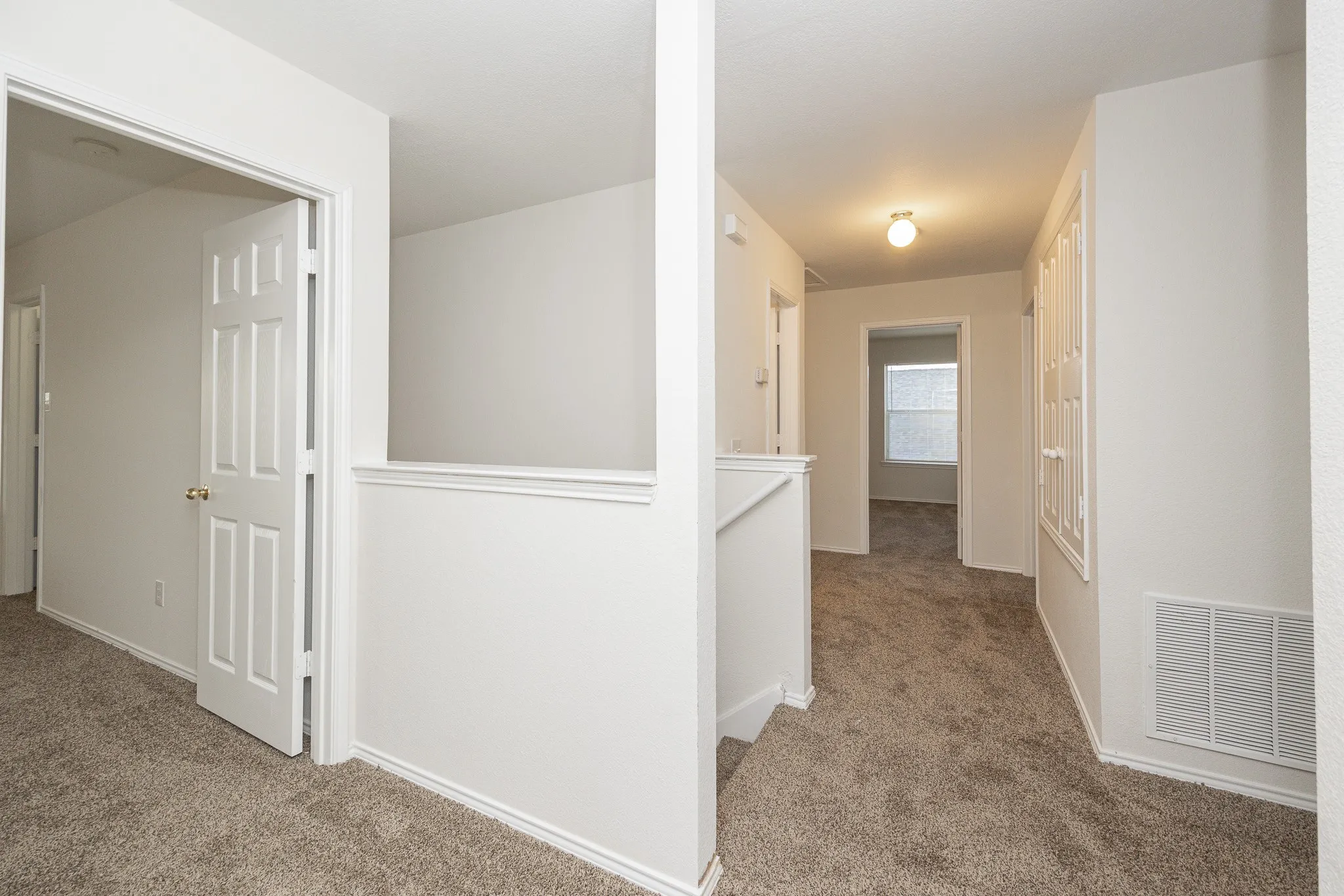 Interior hallway featuring neutral-toned carpeting, white trim, and a semi-flush mount ceiling light fixture