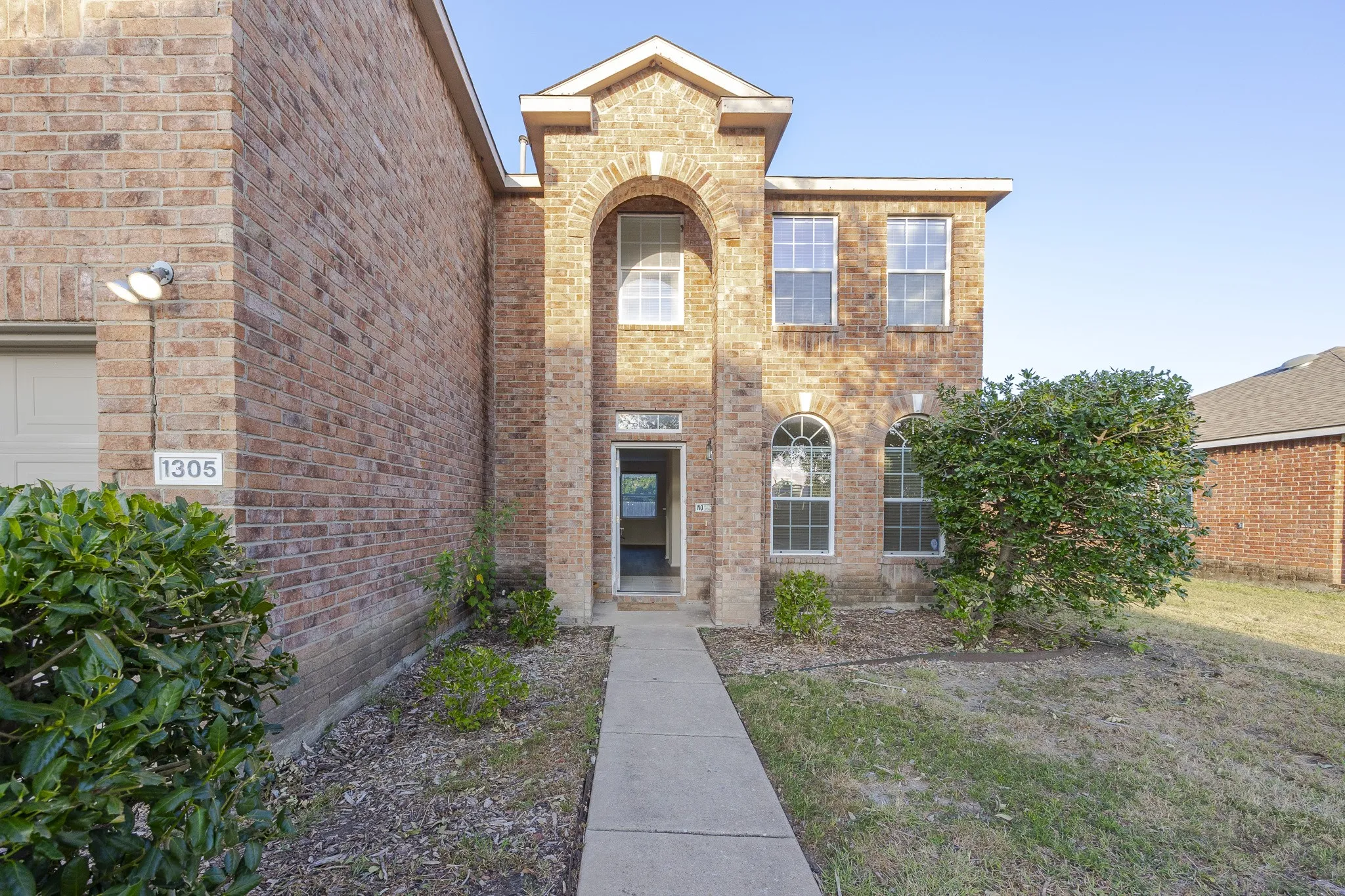 Brick exterior with arched entryway, multi-pane windows, and a concrete pathway