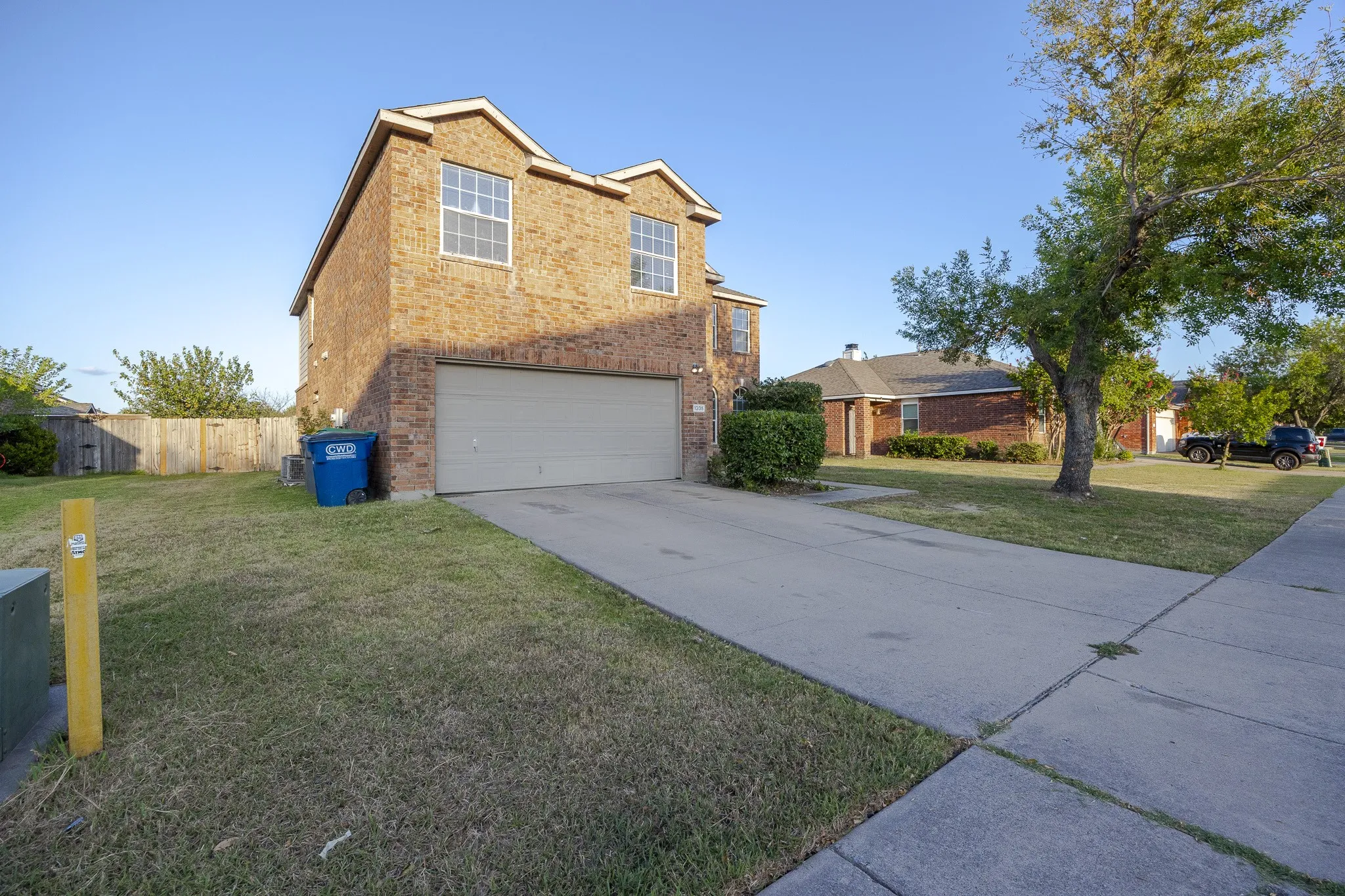 Brick exterior with two stories, an attached garage, and a concrete driveway