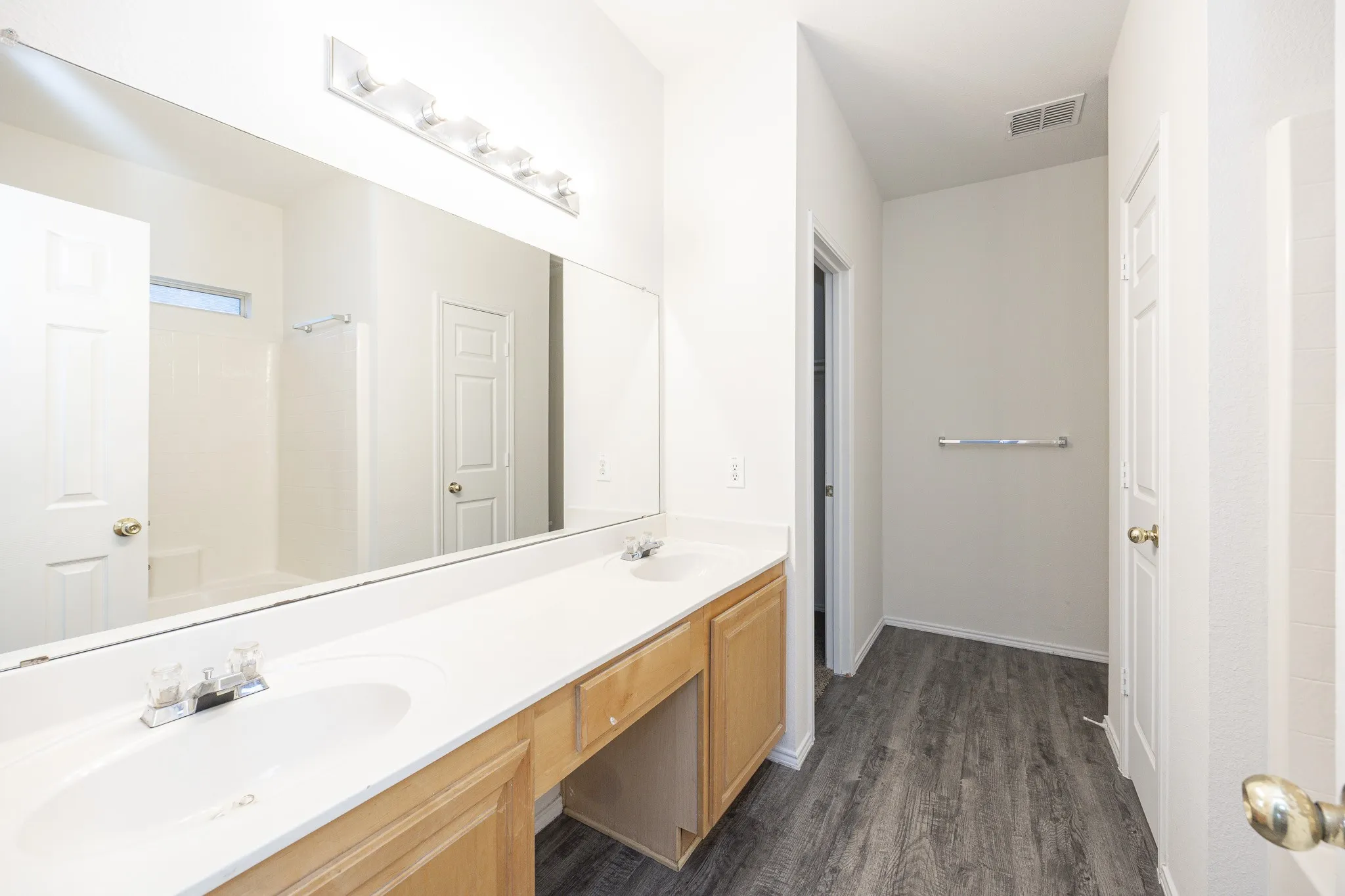 Dual vanity with light wood-finish cabinetry, white countertop, and integrated sinks
