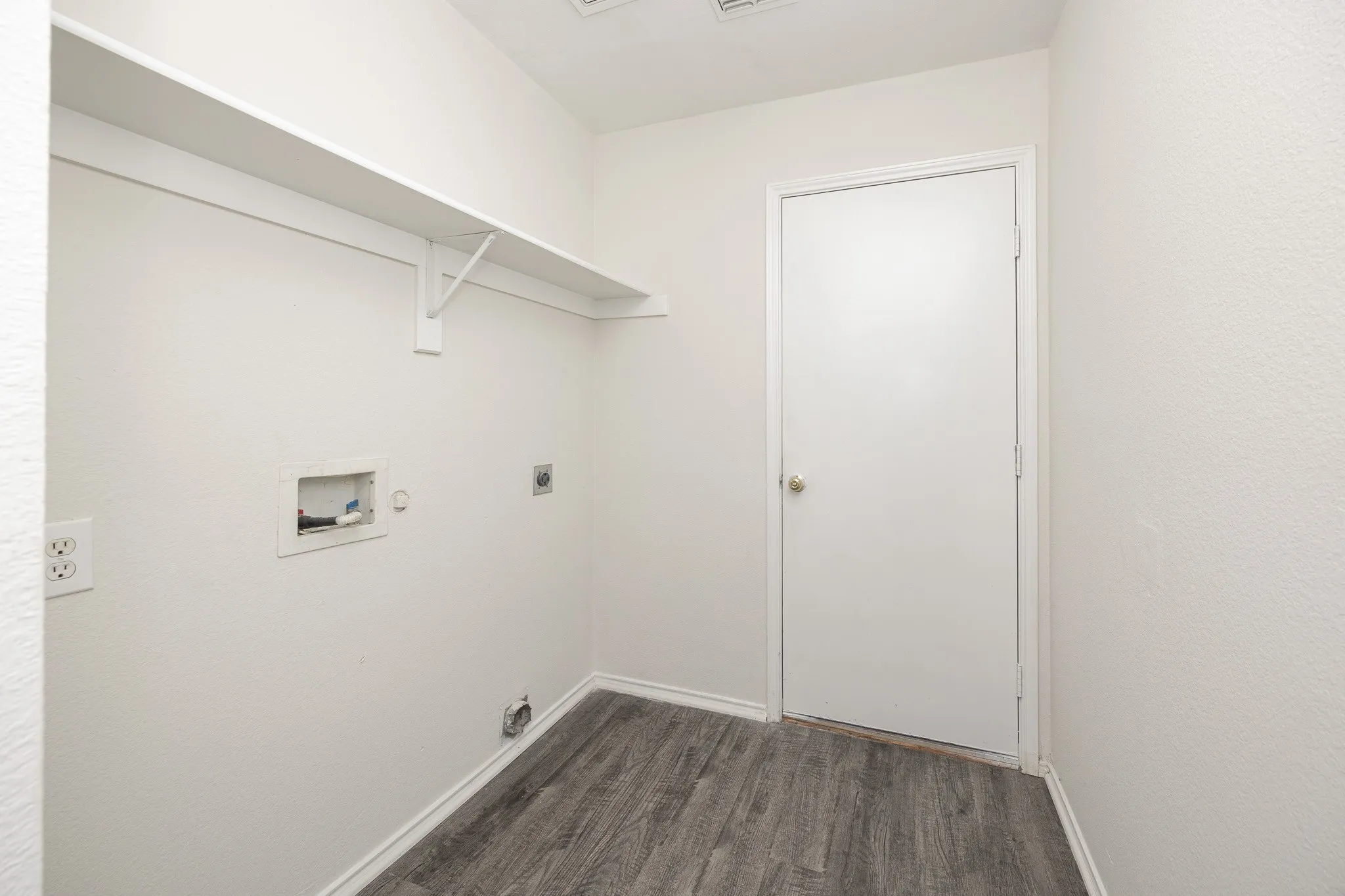 Laundry area with wood-finish flooring, white walls, and built-in shelving