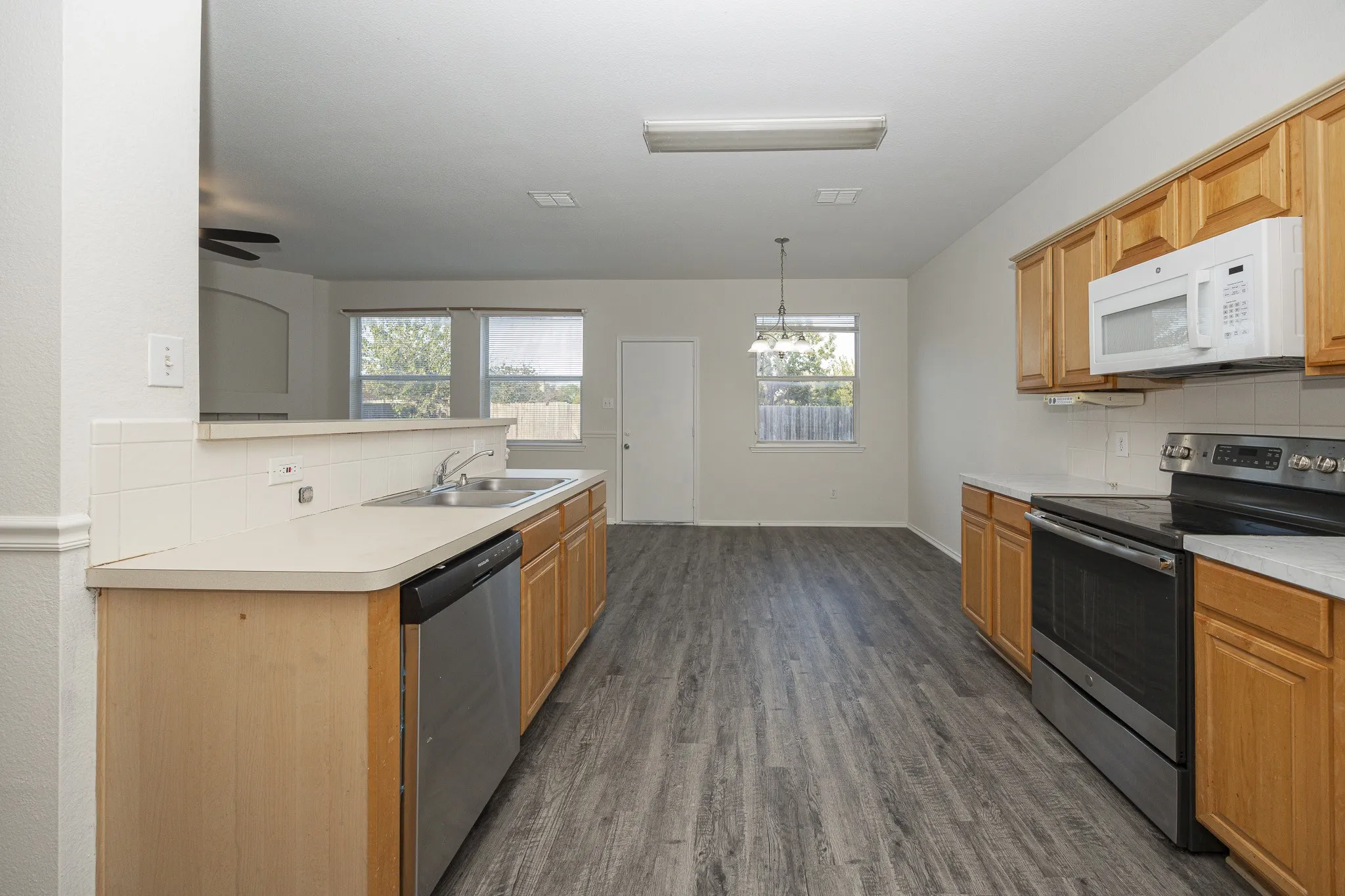 Kitchen featuring wood-finish flooring, light wood cabinetry, white countertops, and stainless steel appliances