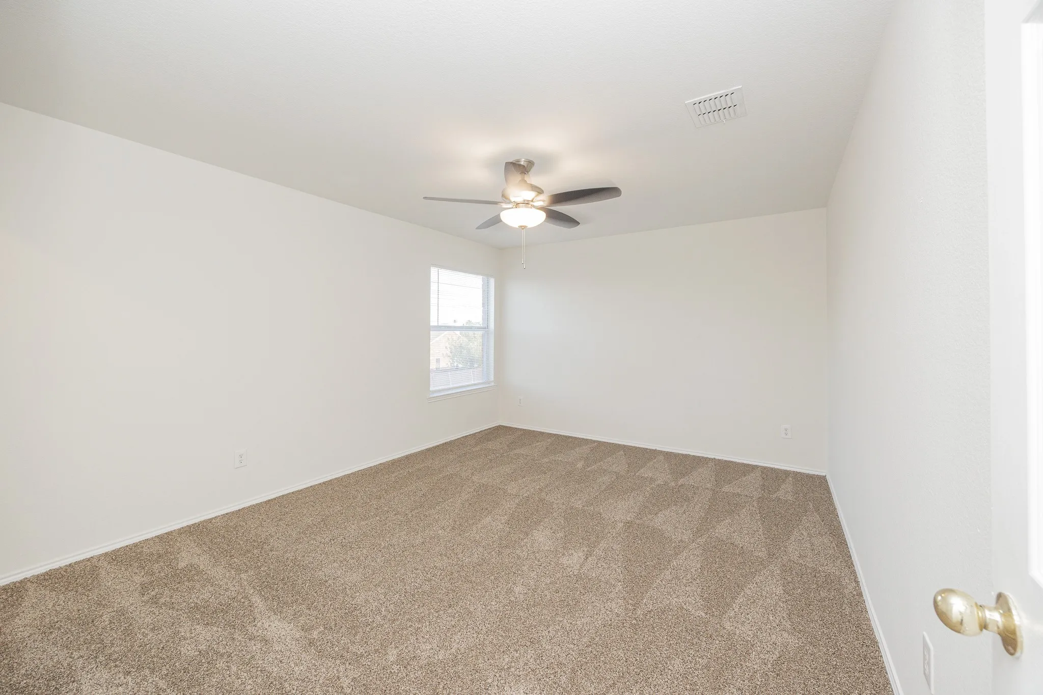 Spacious bedroom with neutral wall finishes, carpet flooring, ceiling fan with integrated lighting, and natural light from a single-hung window