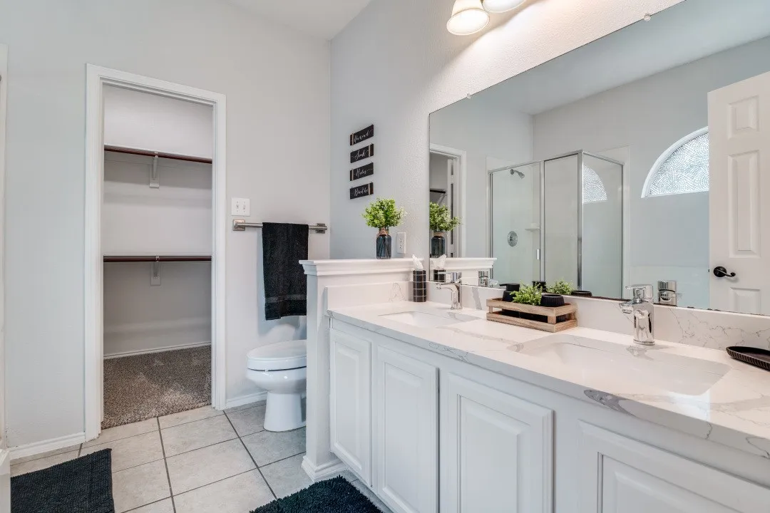 Dual vanity with white cabinetry, stone-look countertops, and chrome fixtures