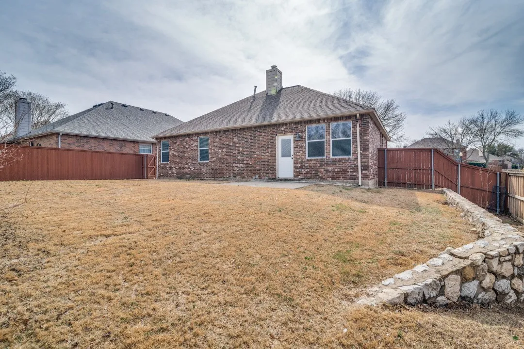 Brick exterior with a gabled roof, rear patio, and a stone retaining wall