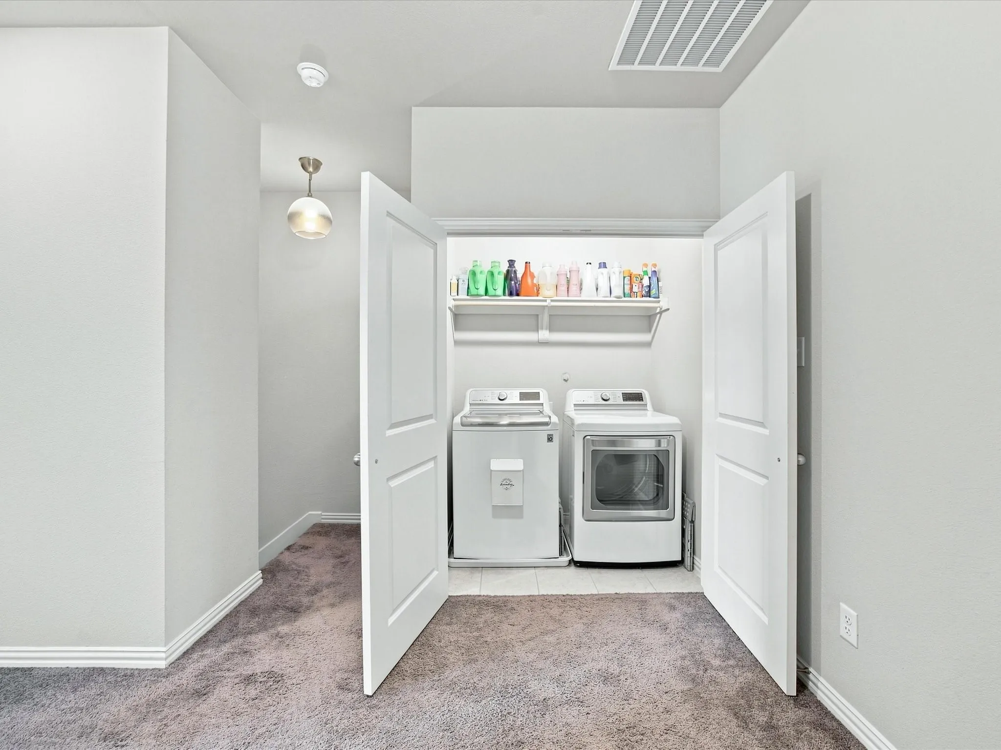Dedicated laundry area with built-in shelving and tile flooring