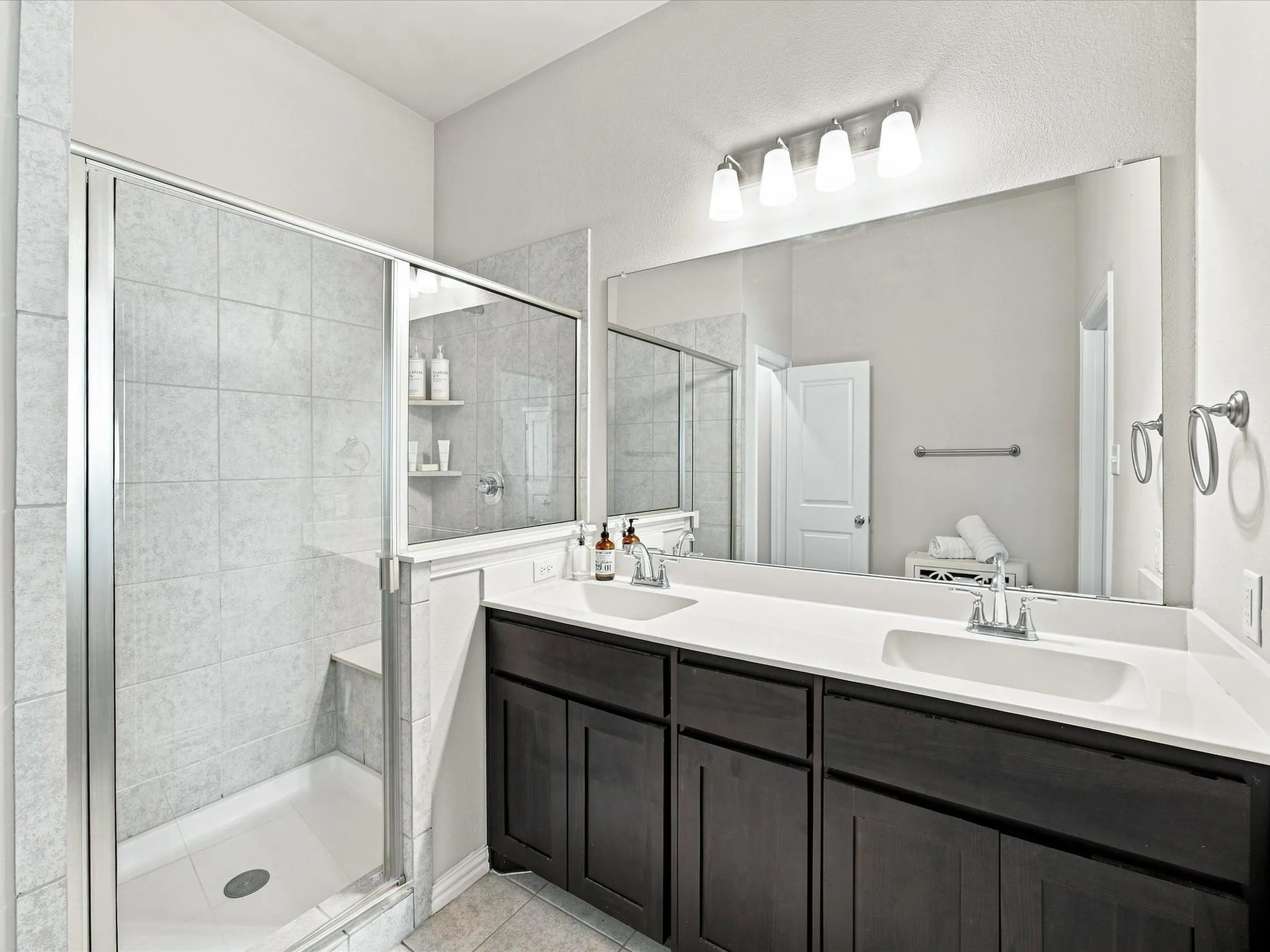 Dual vanity with white countertops and dark wood-finish cabinetry