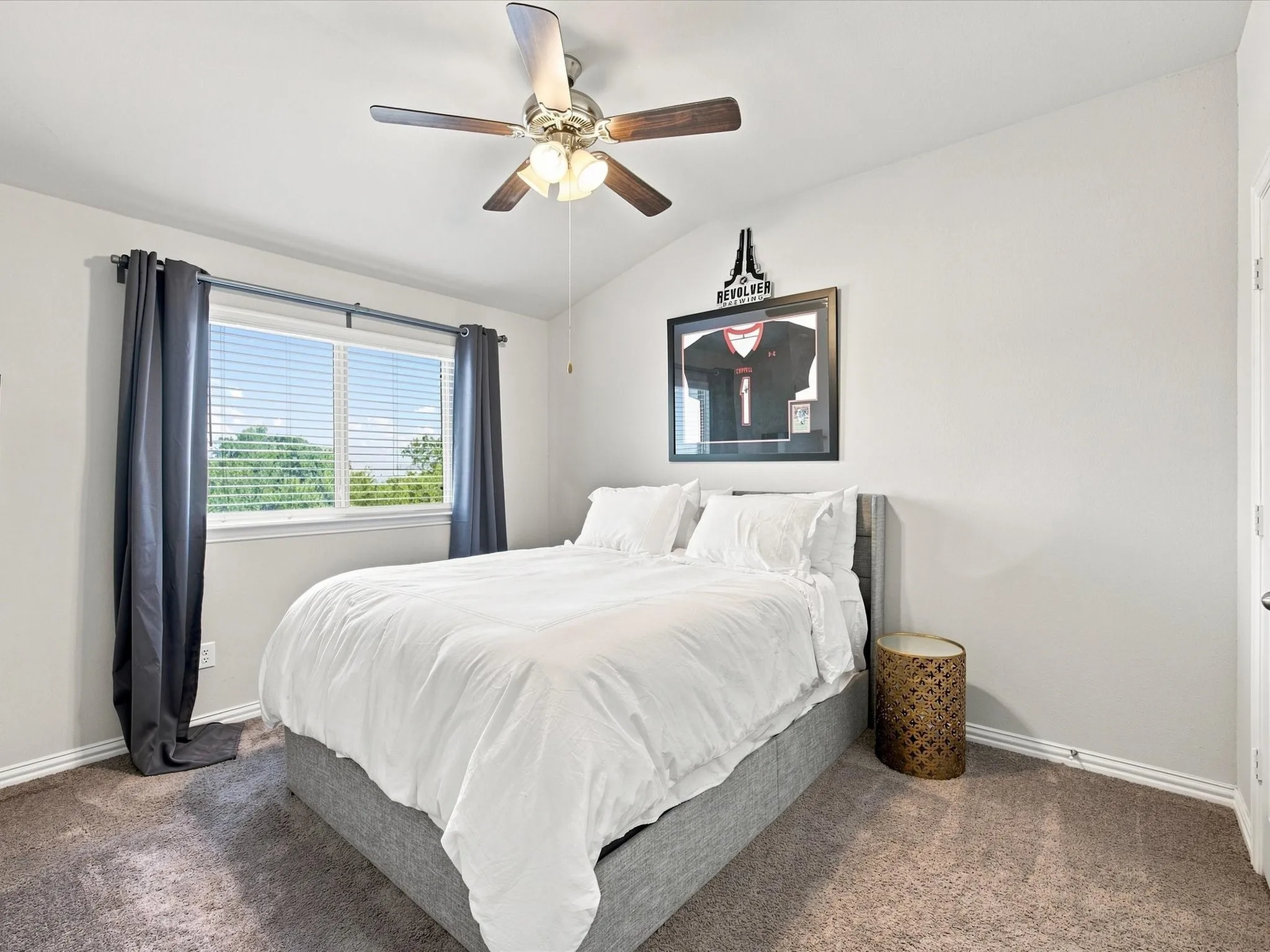Vaulted ceiling, ceiling fan with light fixture, window with blinds, and carpeted flooring