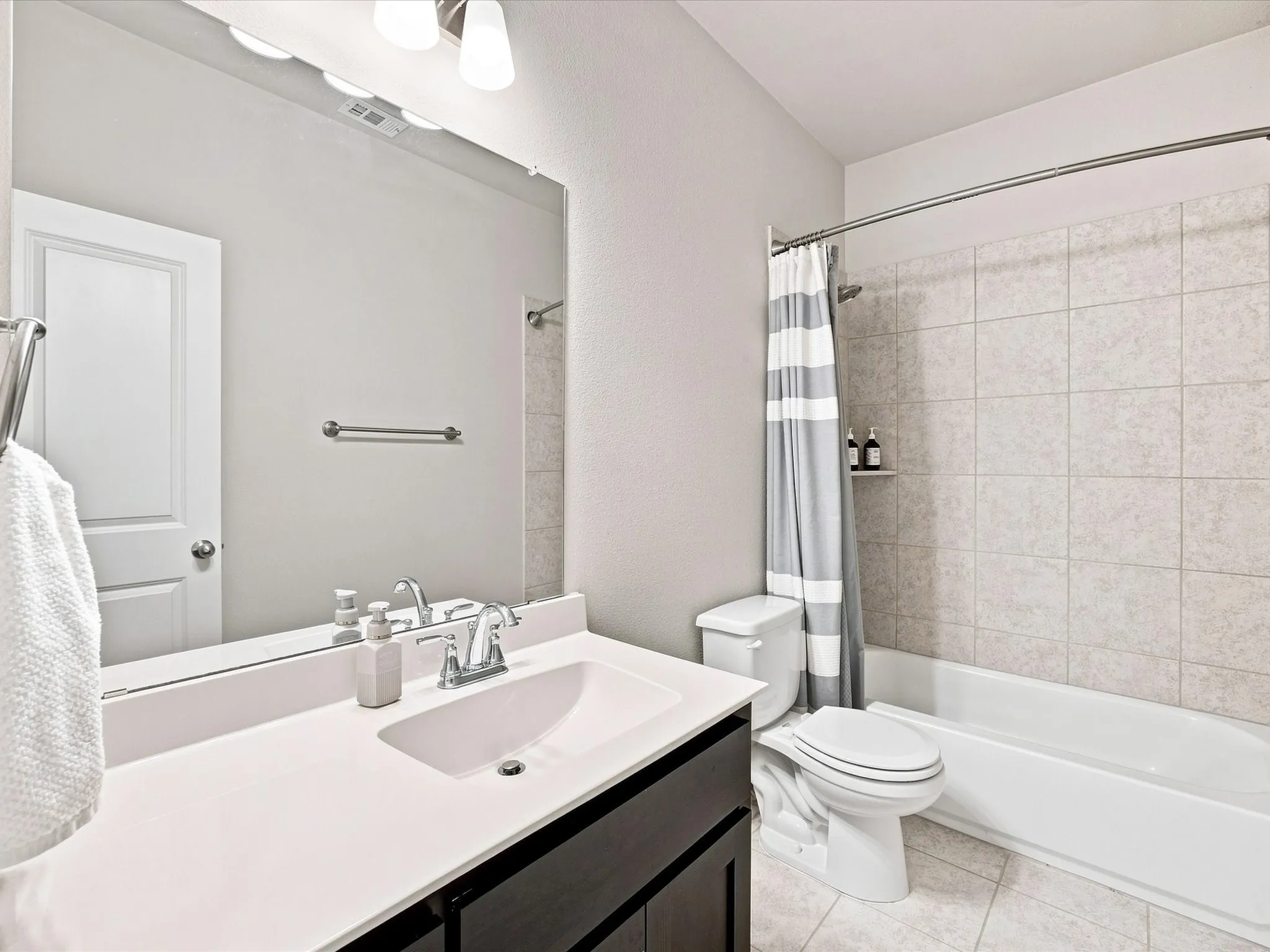 Vanity with integrated sink, dark wood-finish cabinetry, and framed mirror