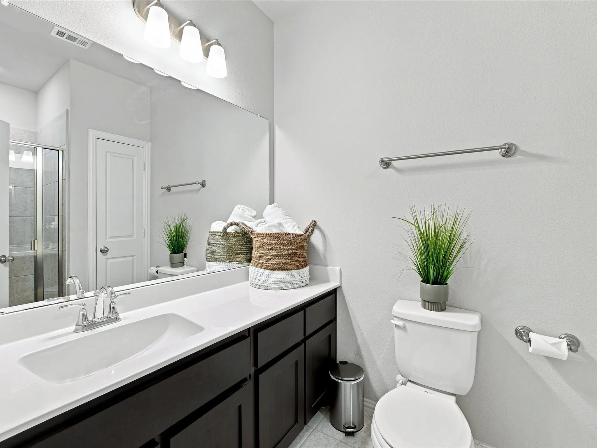 Integrated vanity with a single basin, dark wood-finish cabinetry, and a full-width mirror