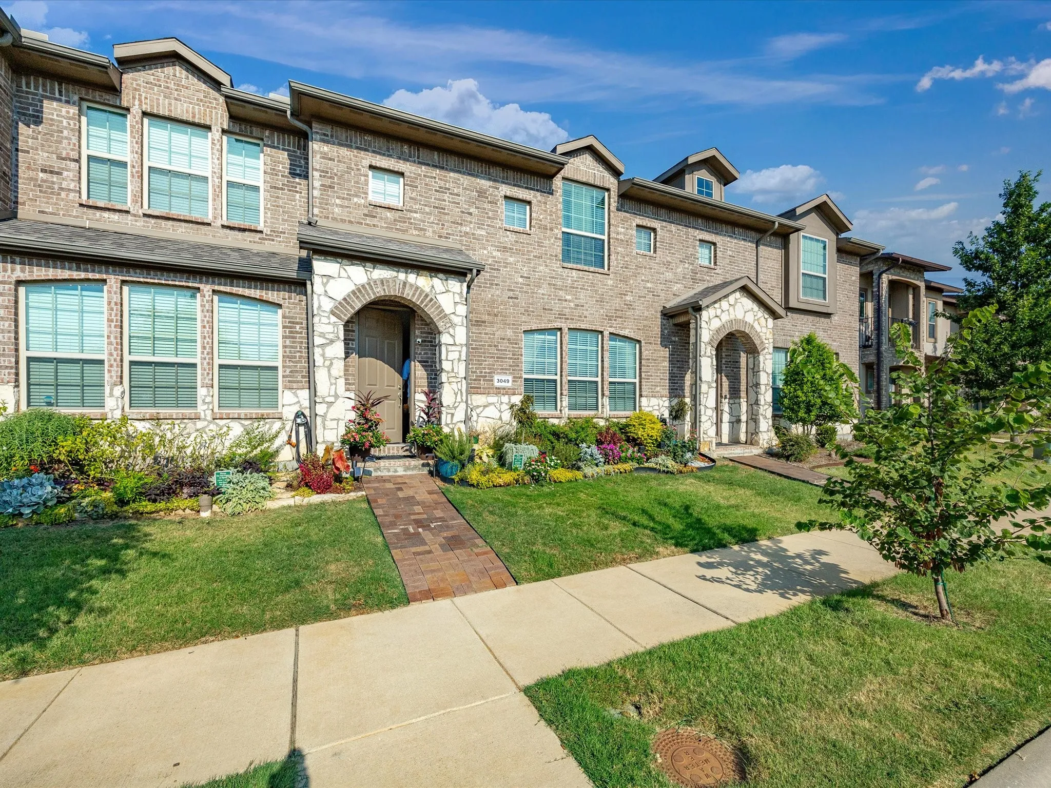 Brick and stone veneer exterior with arched entryways, multiple windows, and a landscaped front yard