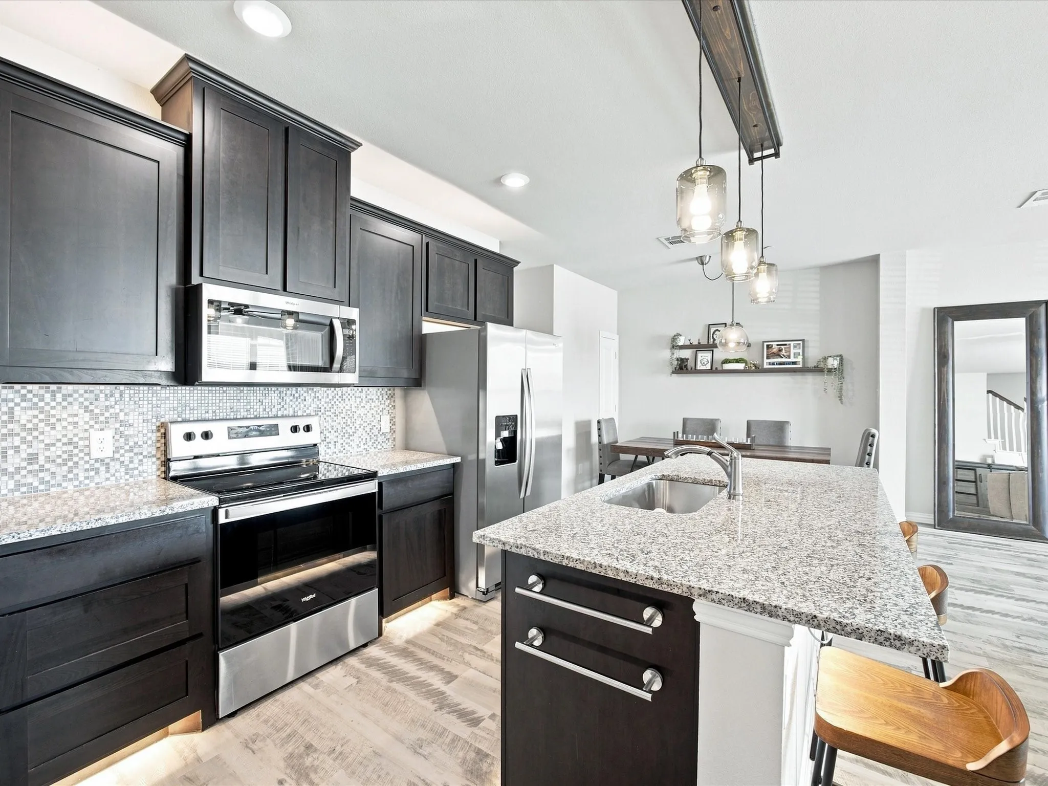 Modern kitchen with dark cabinetry, stainless steel appliances, and light-toned countertops