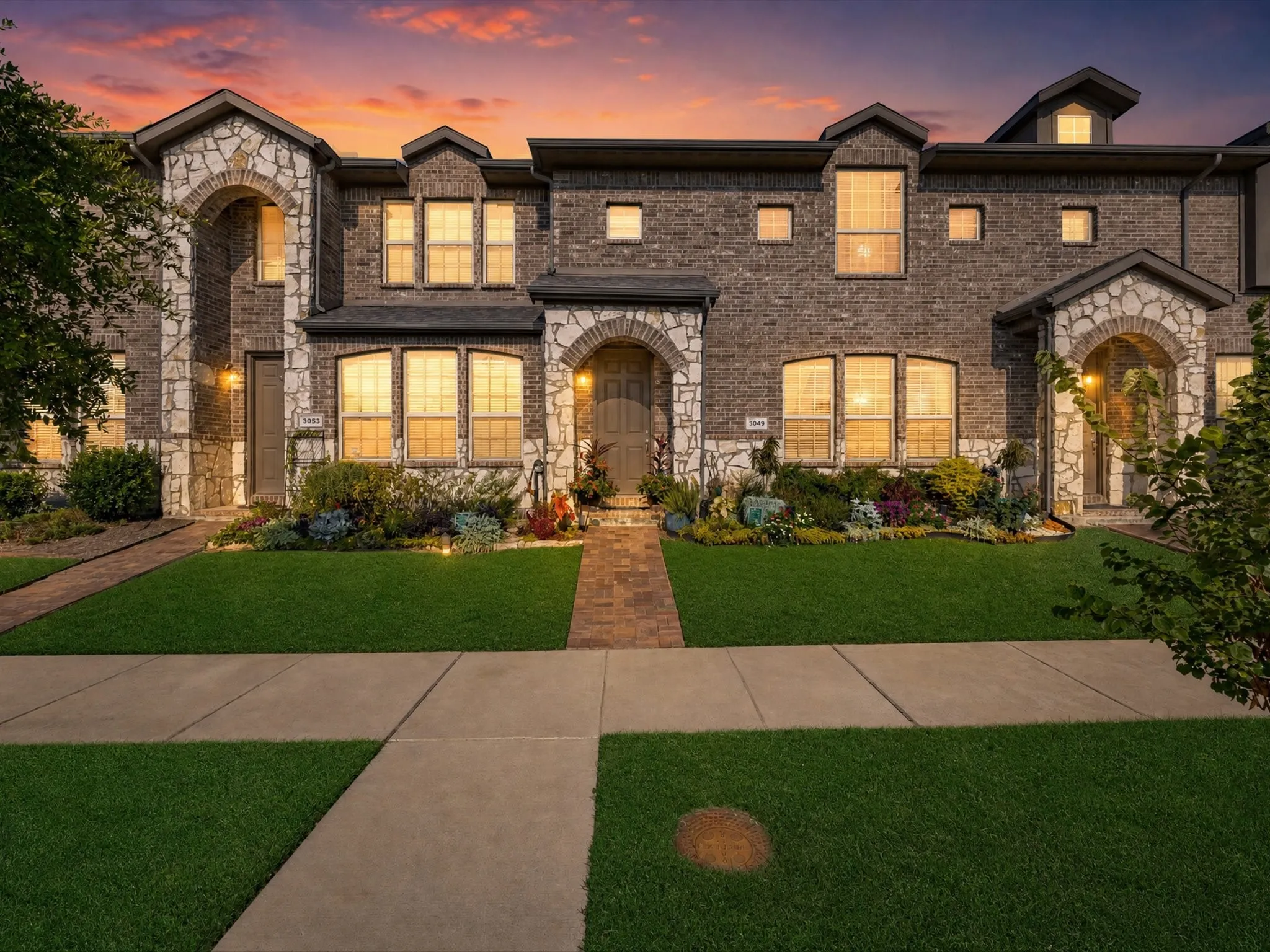 Stone and brick exterior with arched entryways, multiple windows, and a brick pathway