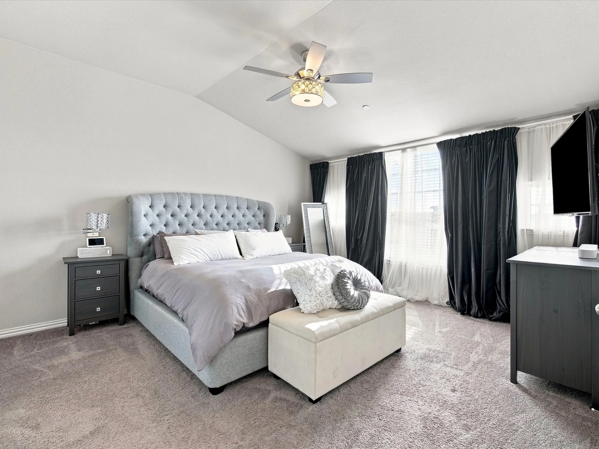 Vaulted ceiling with a ceiling fan, carpeted flooring, and multiple windows