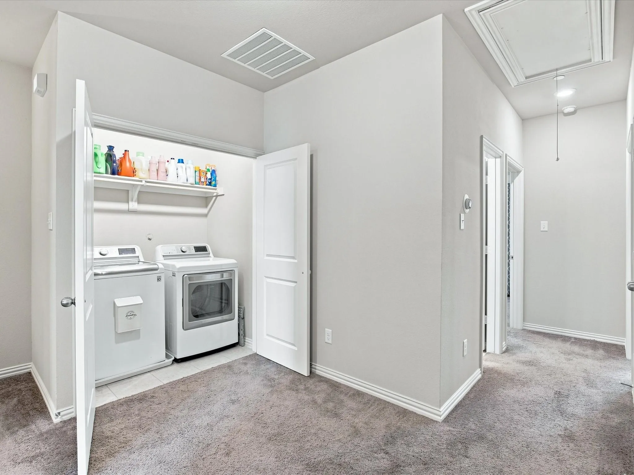 Dedicated laundry area featuring a washer and dryer, tile flooring, and integrated shelving