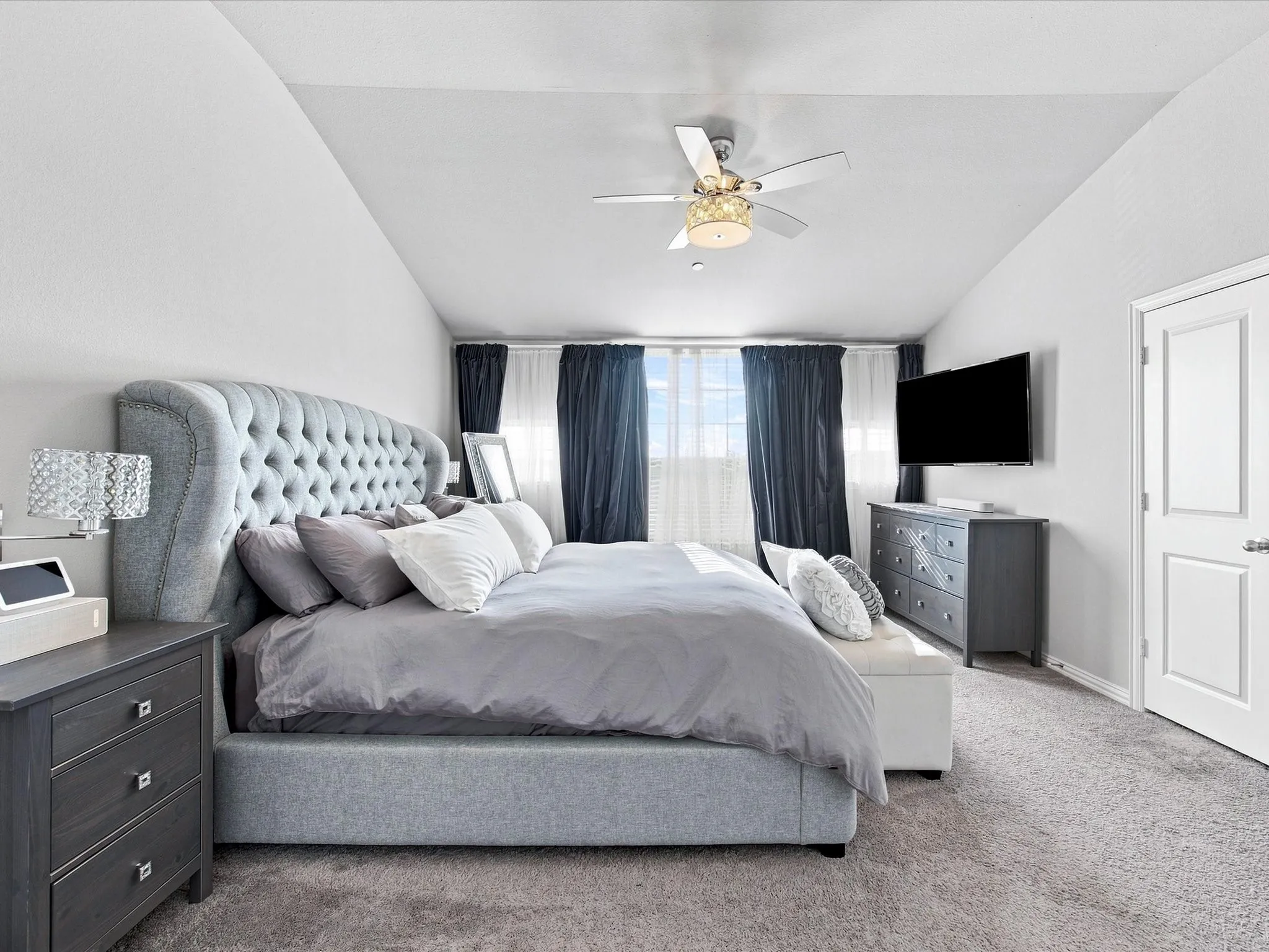 Carpeted flooring, vaulted ceiling, ceiling fan, and white paneled door